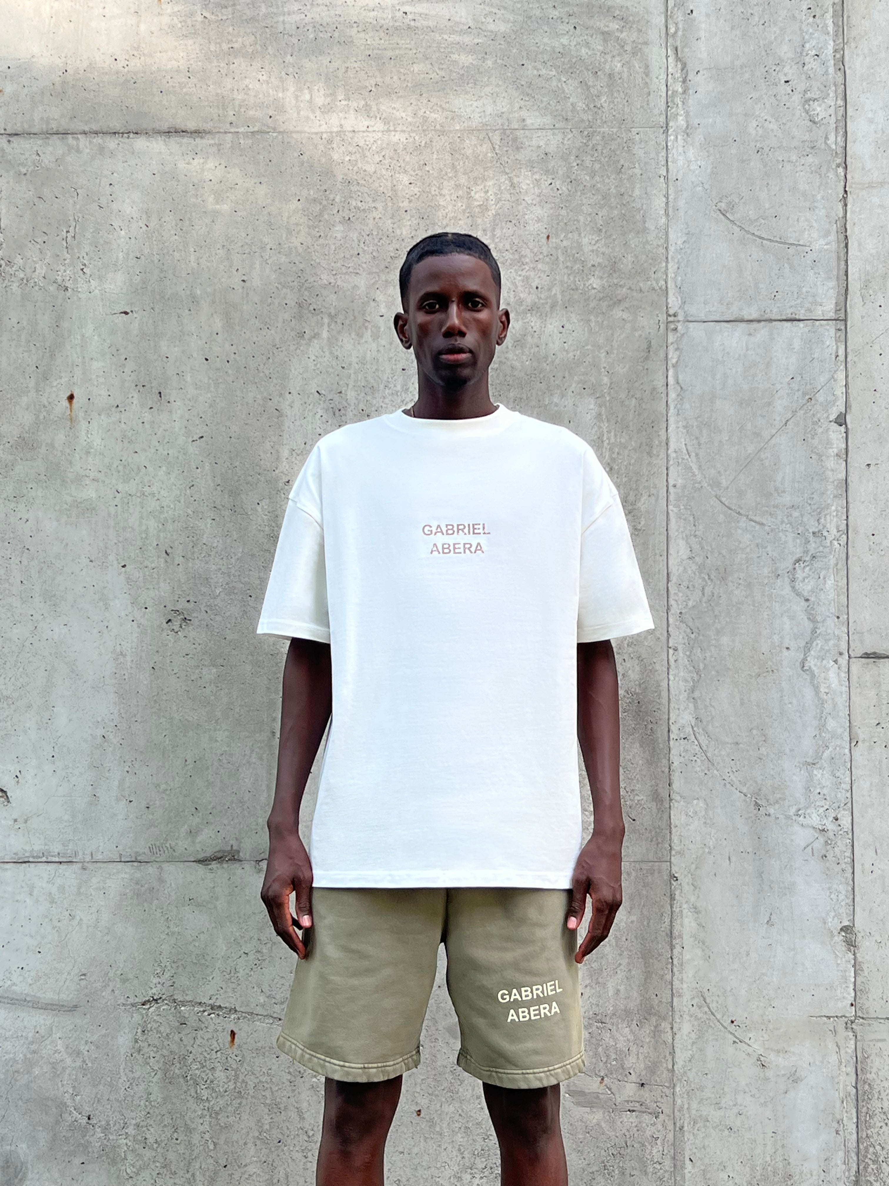 Model wearing GA T-Shirt in cream white with khaki GA logo, relaxed fit, front view