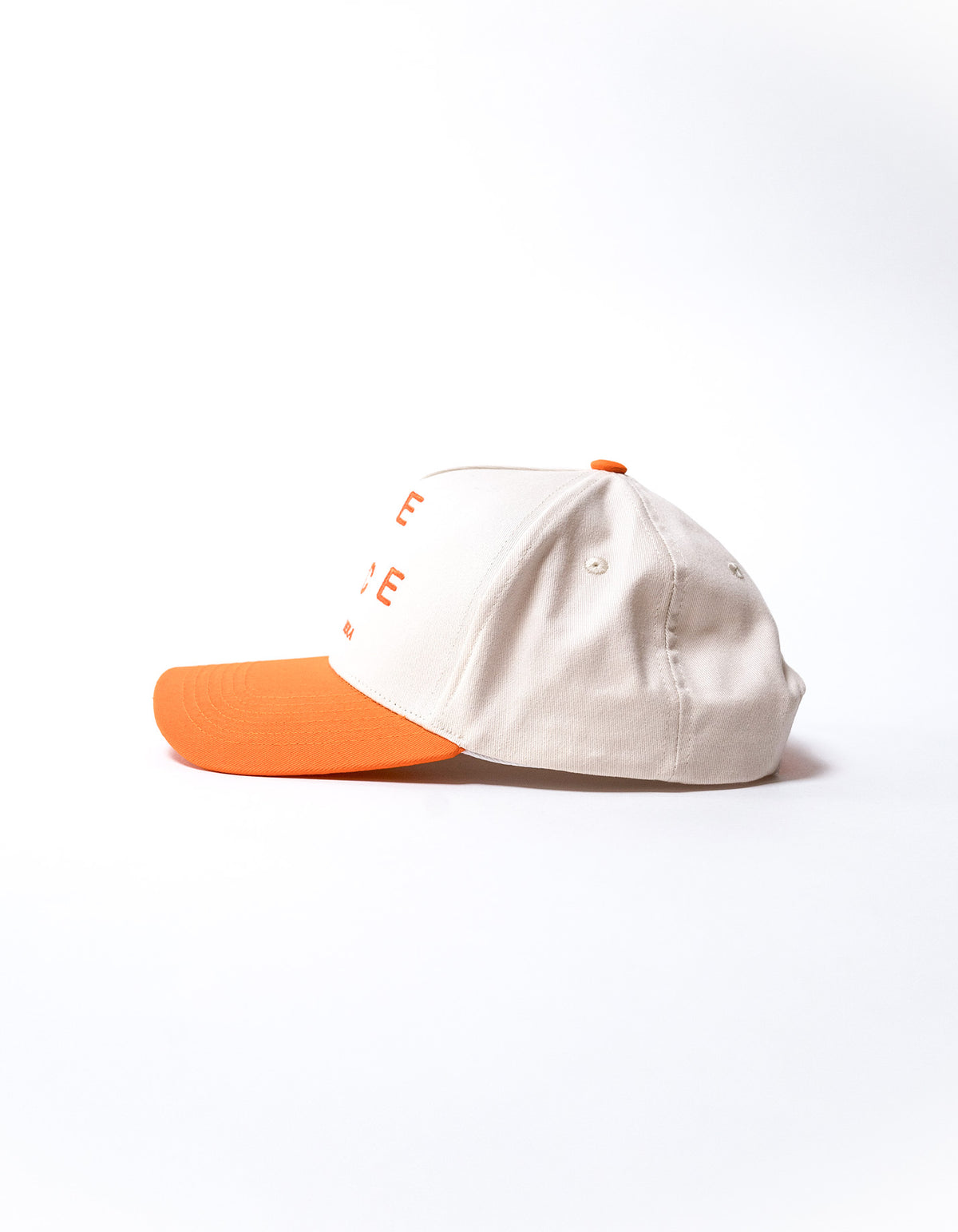 White cap with orange shield with "be nice" writing on the front