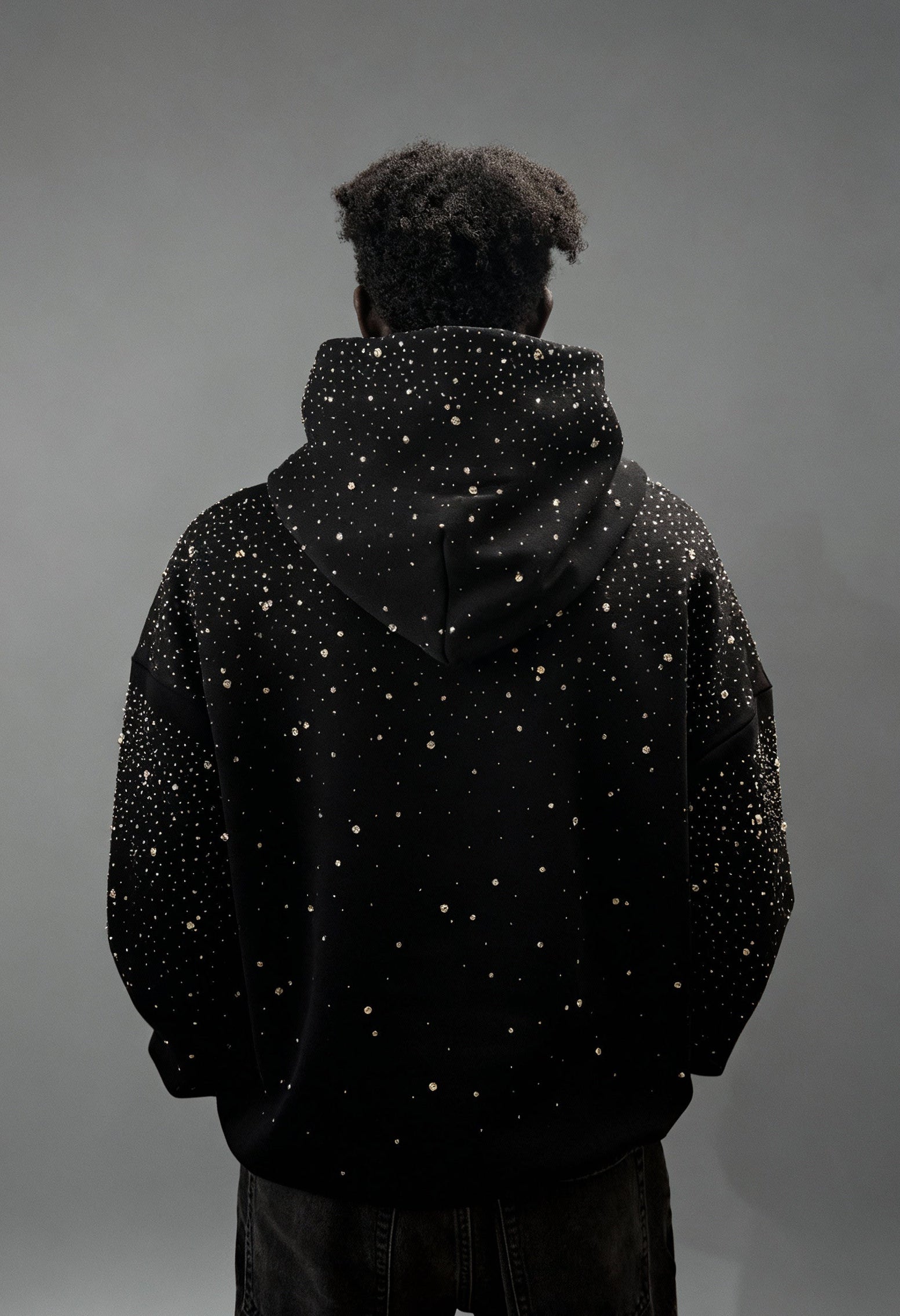 Schwarzer GABRIEL ABERA Rhinestone Hoodie – männliches Model von hinten gezeigt, Rhinestones auf Kapuze und Rücken glitzern.