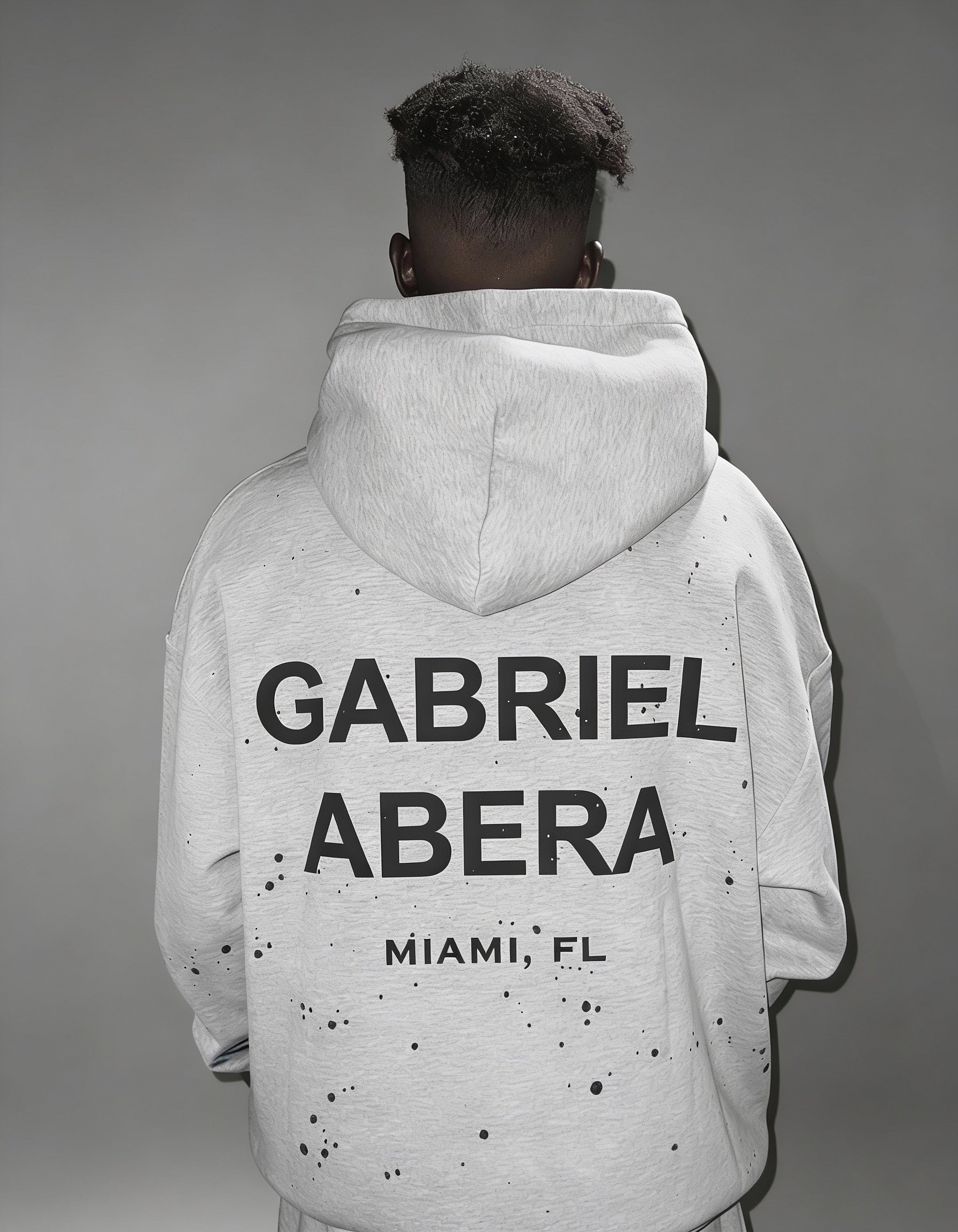 Männliches Model trägt GABRIEL ABERA Splattered Hoodie in grau – Rückenansicht, Oversized Premium Streetwear Fit.