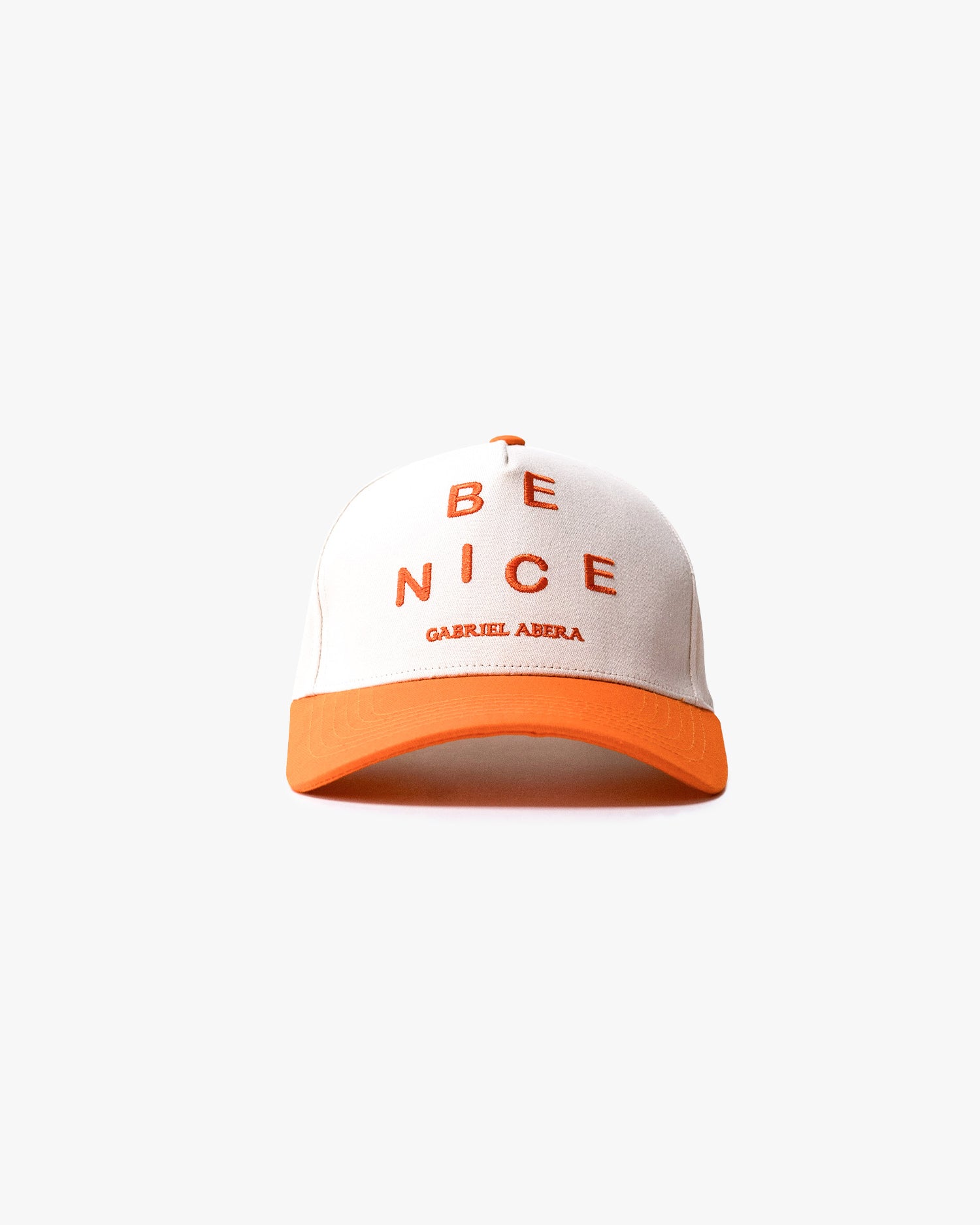 White cap with orange shield with "be nice" writing on the front