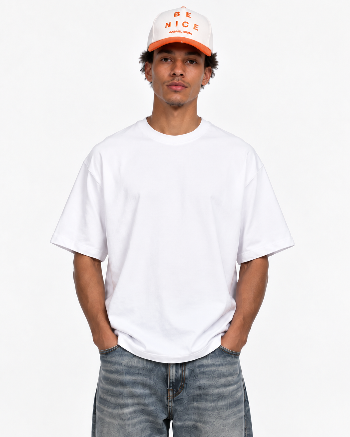 Männliches Model trägt die cream-weiße GABRIEL ABERA Be Nice Snapback mit orangefarbenem Stickerei-Design