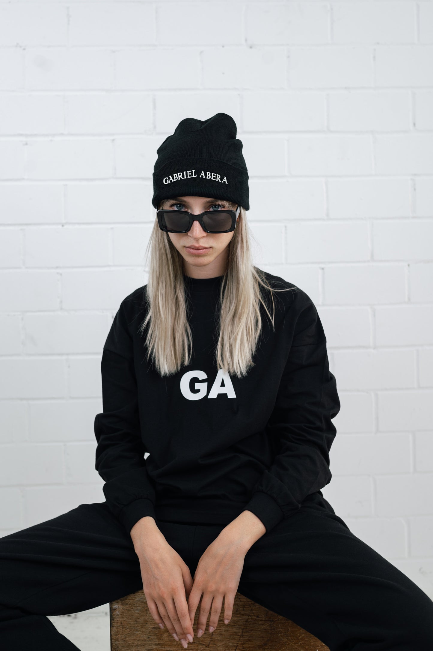 Female model wearing a Black beanie with brand name embroidery