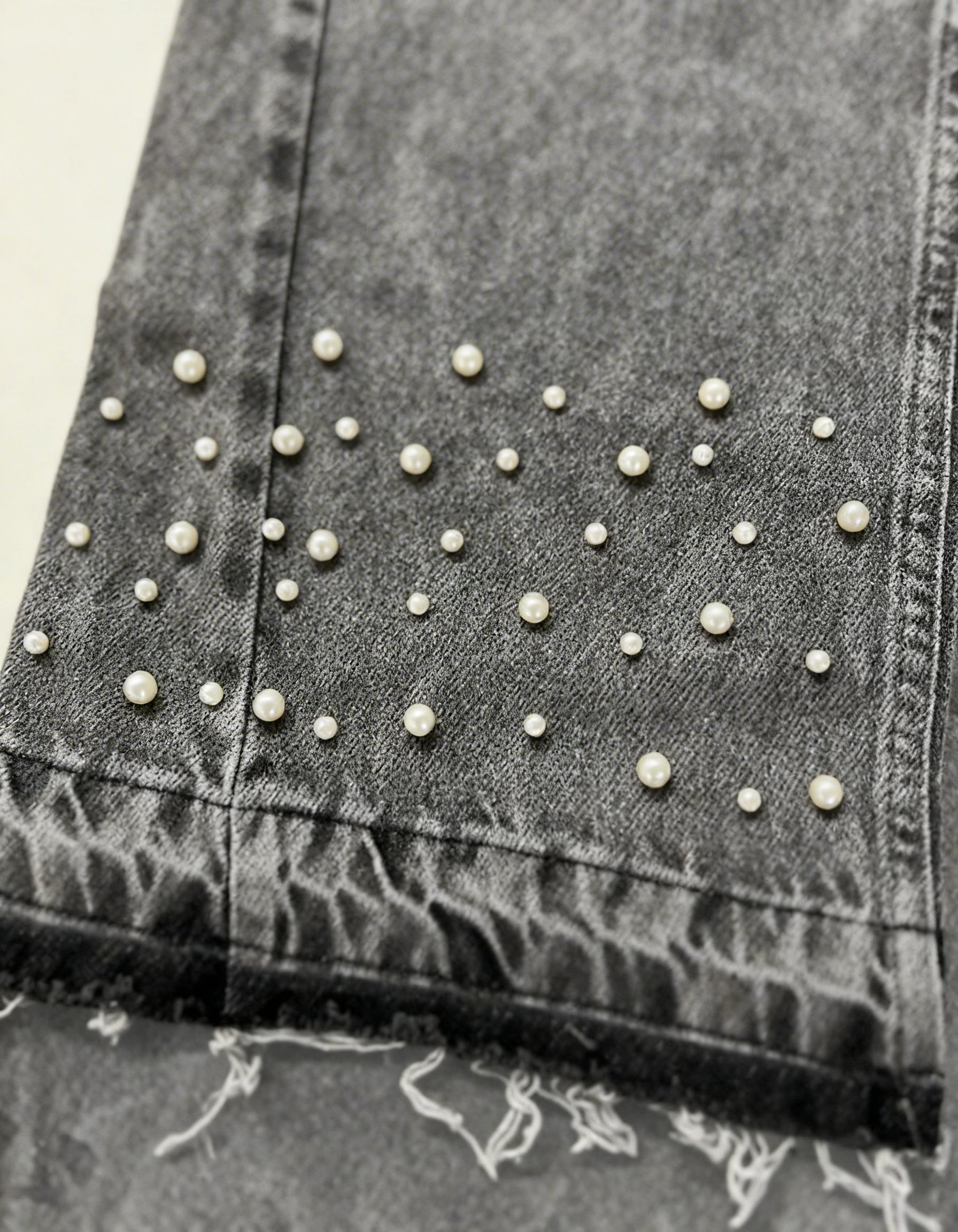 Close-up of hand-placed pearls on grey stonewashed denim jeans by GABRIEL ABERA.