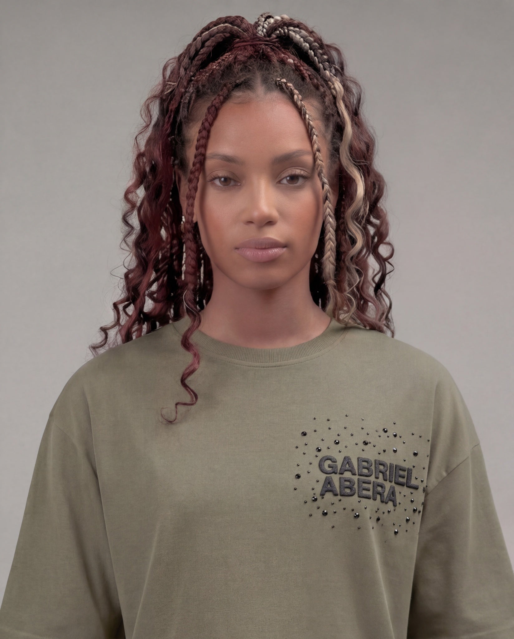Femail model with Close-up of the rhinestone 'Gabriel Abera' logo on the olive / green tee – scattered crystal lettering on washed olive cotton fabric