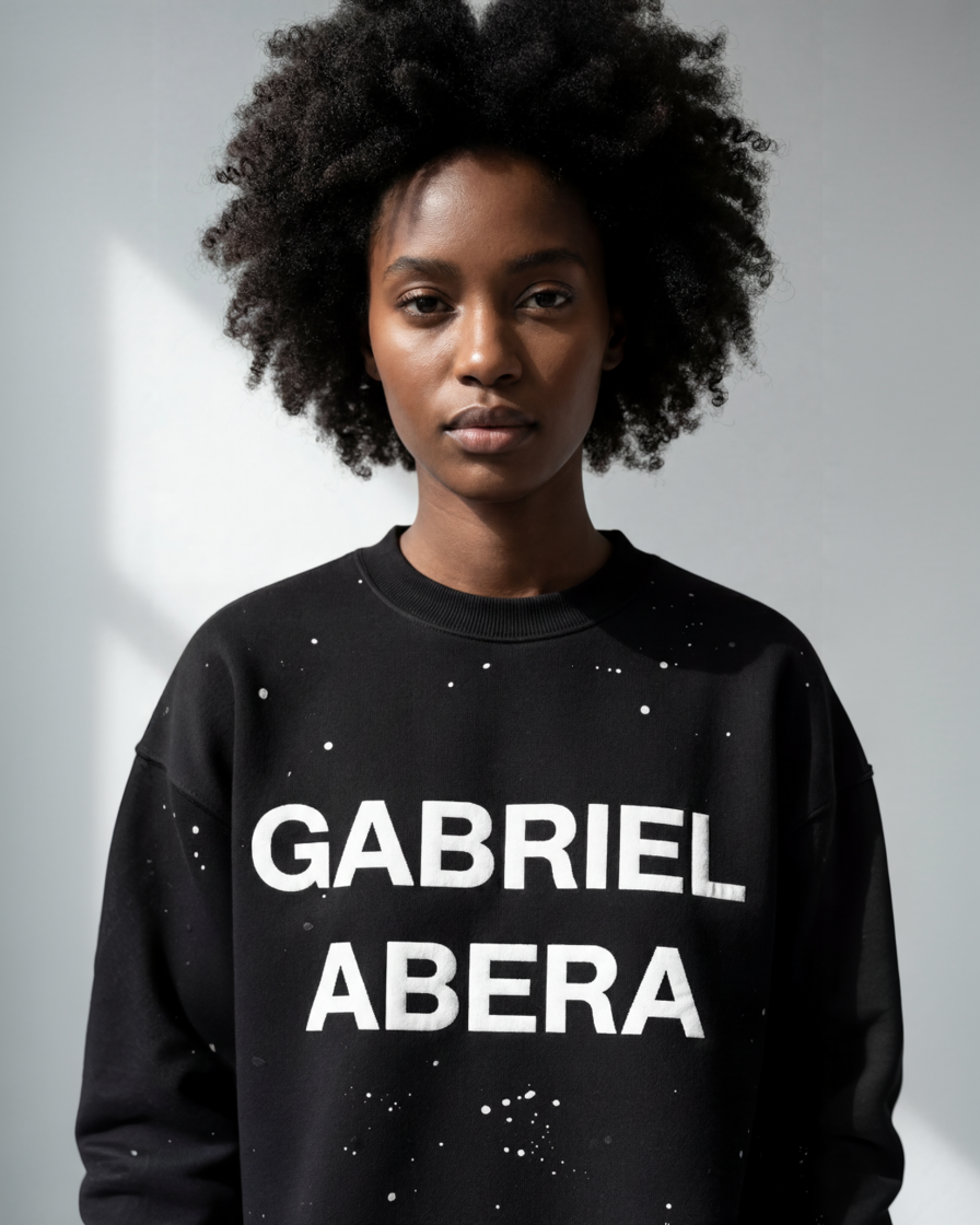 Detailaufnahme des schwarzen GABRIEL ABERA Sweaters mit individueller Splatter-Optik, hochwertiger Baumwollstruktur und präziser Verarbeitung.