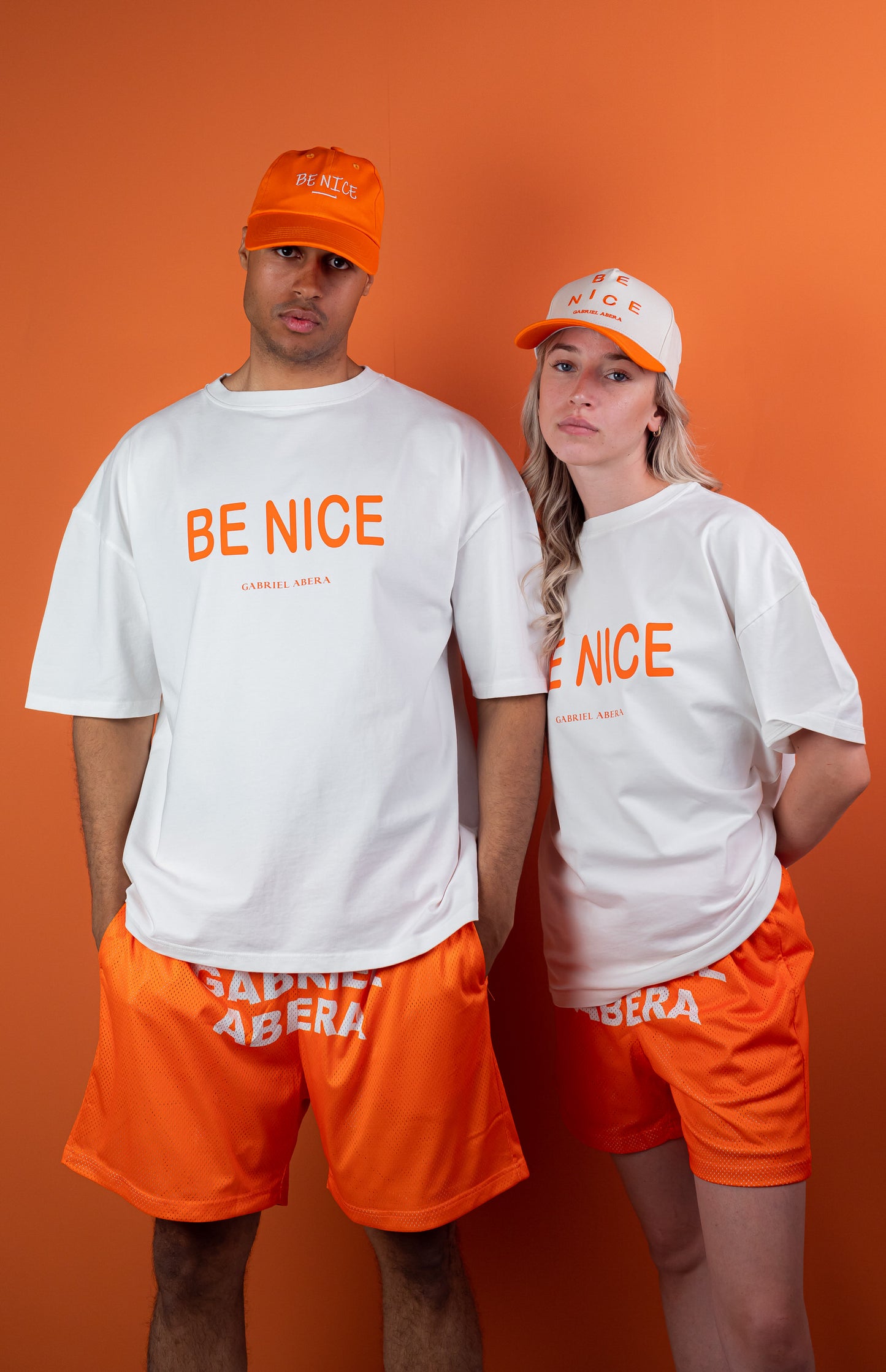 Female and Male Model wearing White oversize tshirt with orange "be nice" print on the front 