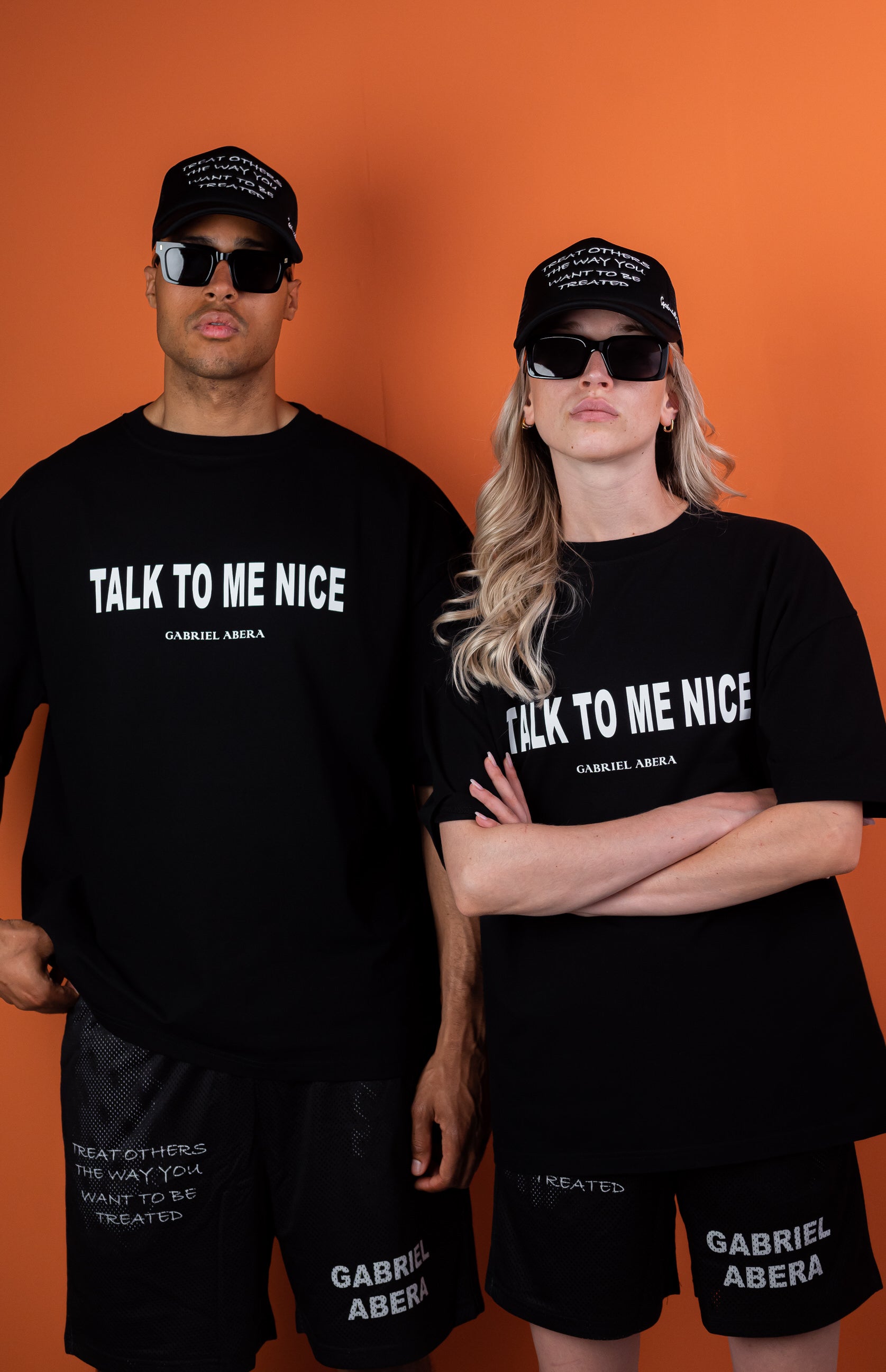 Male and female model wearing a Black oversize tshirt with white talk to me nice design on the front