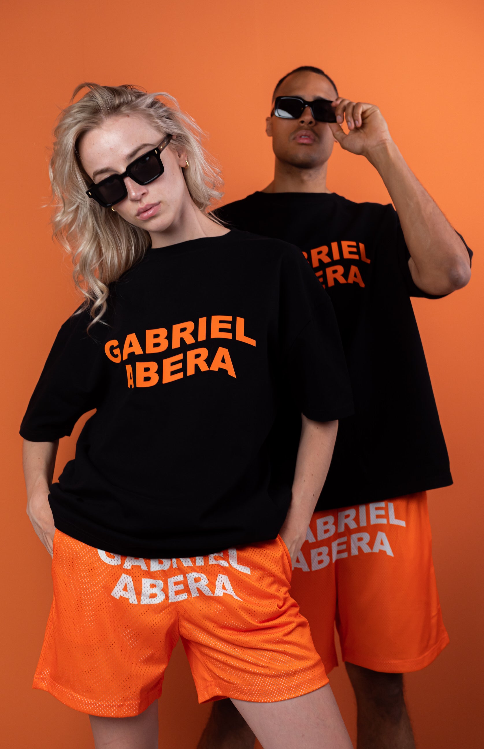 models wearing black oversie tshirt with orange wavy brand name design