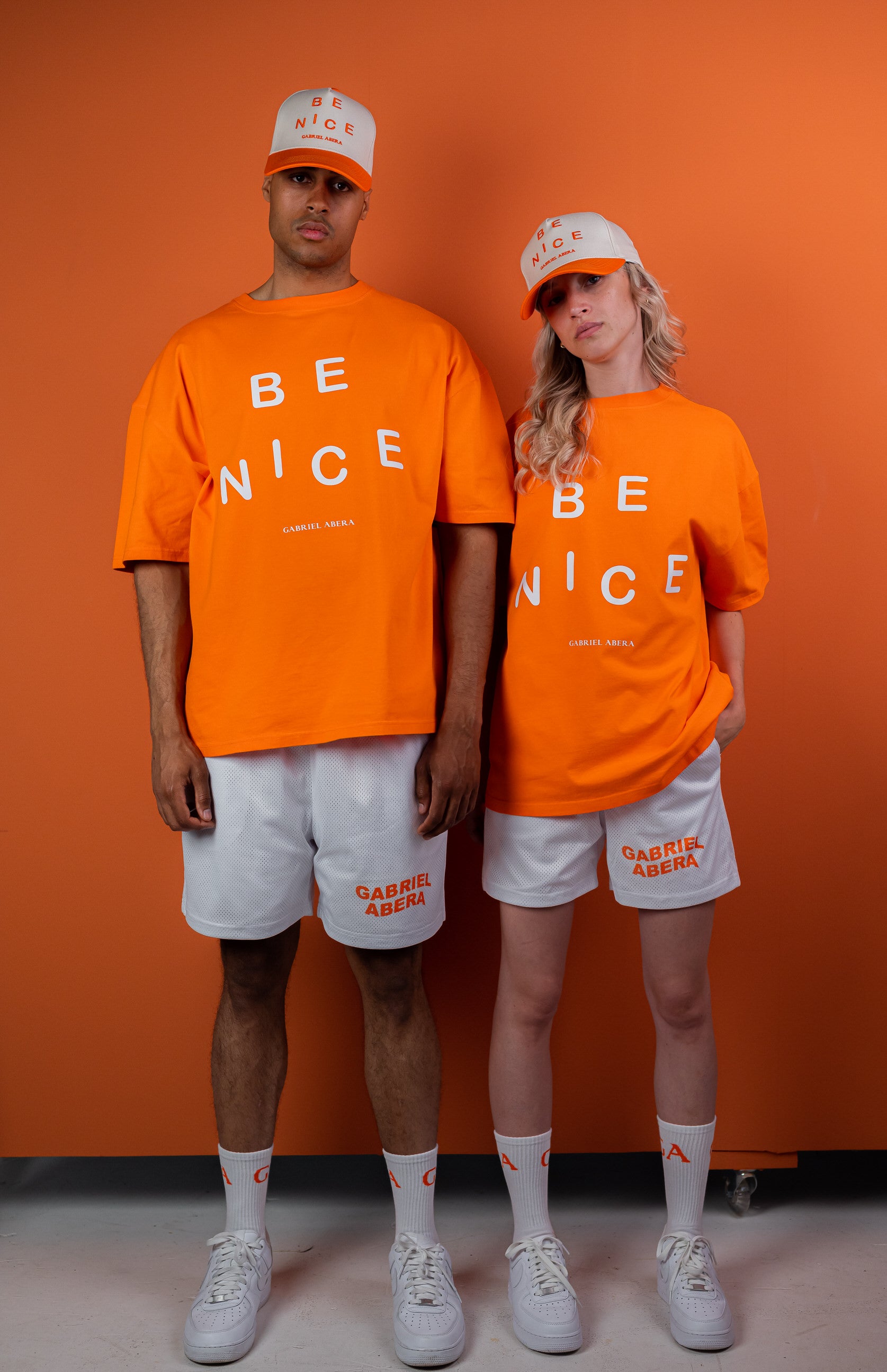 Male and female Models wearing Orange oversize tshirt with "be nice" print on the front 