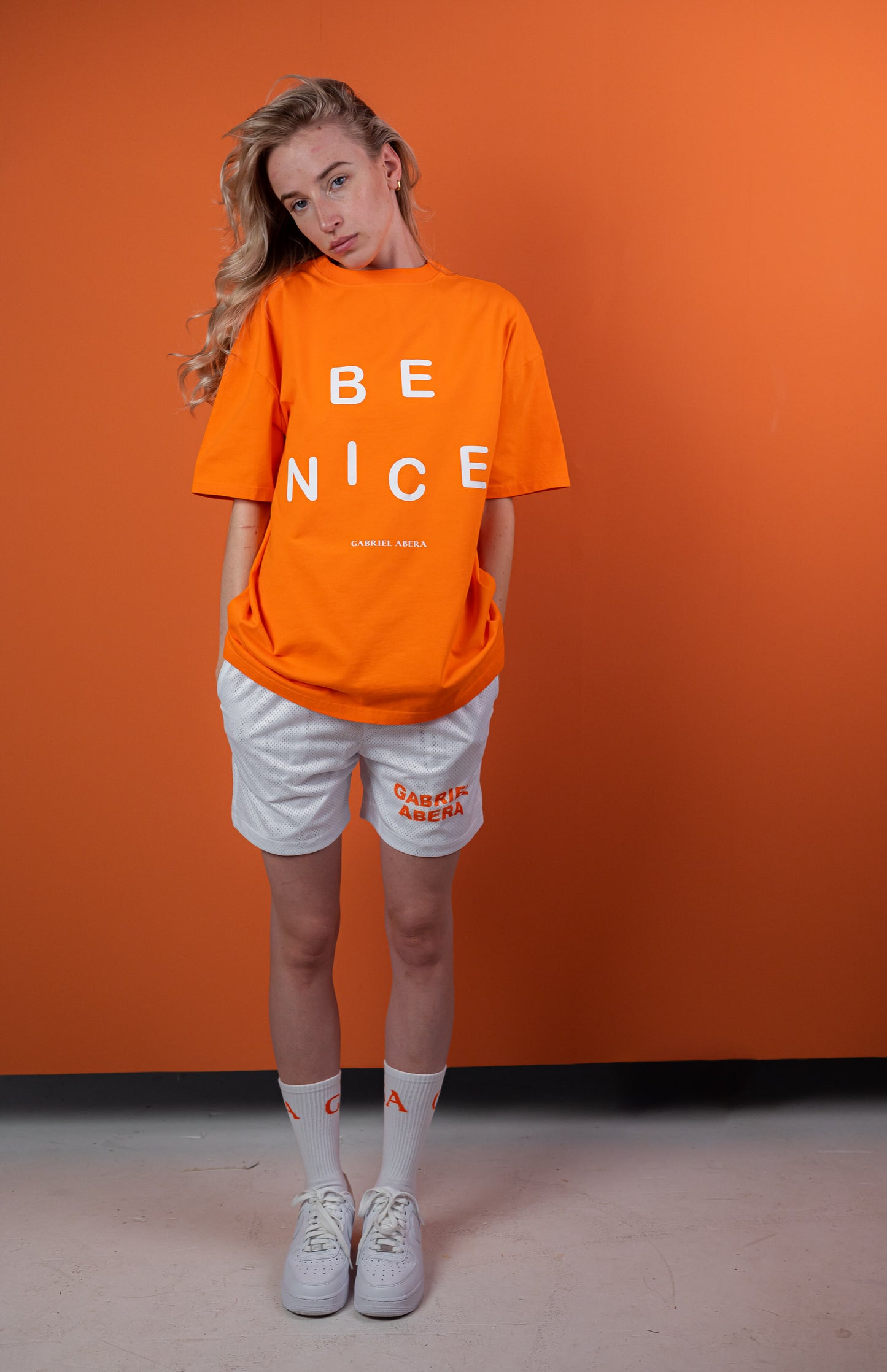 Female Model wearing Orange oversize tshirt with "be nice" print on the front 