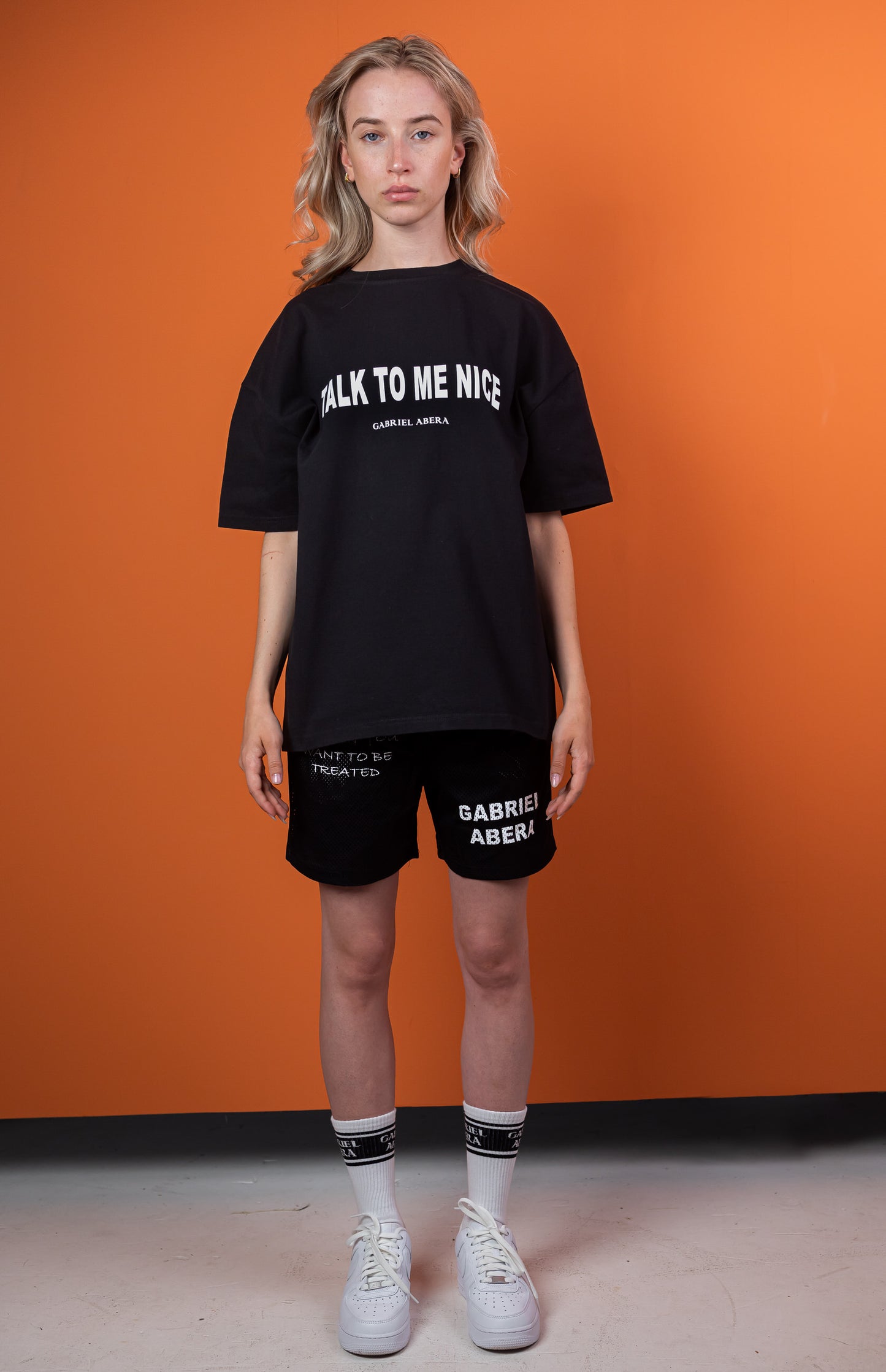 Female model wearing a Black oversize tshirt with white talk to me nice design on the front