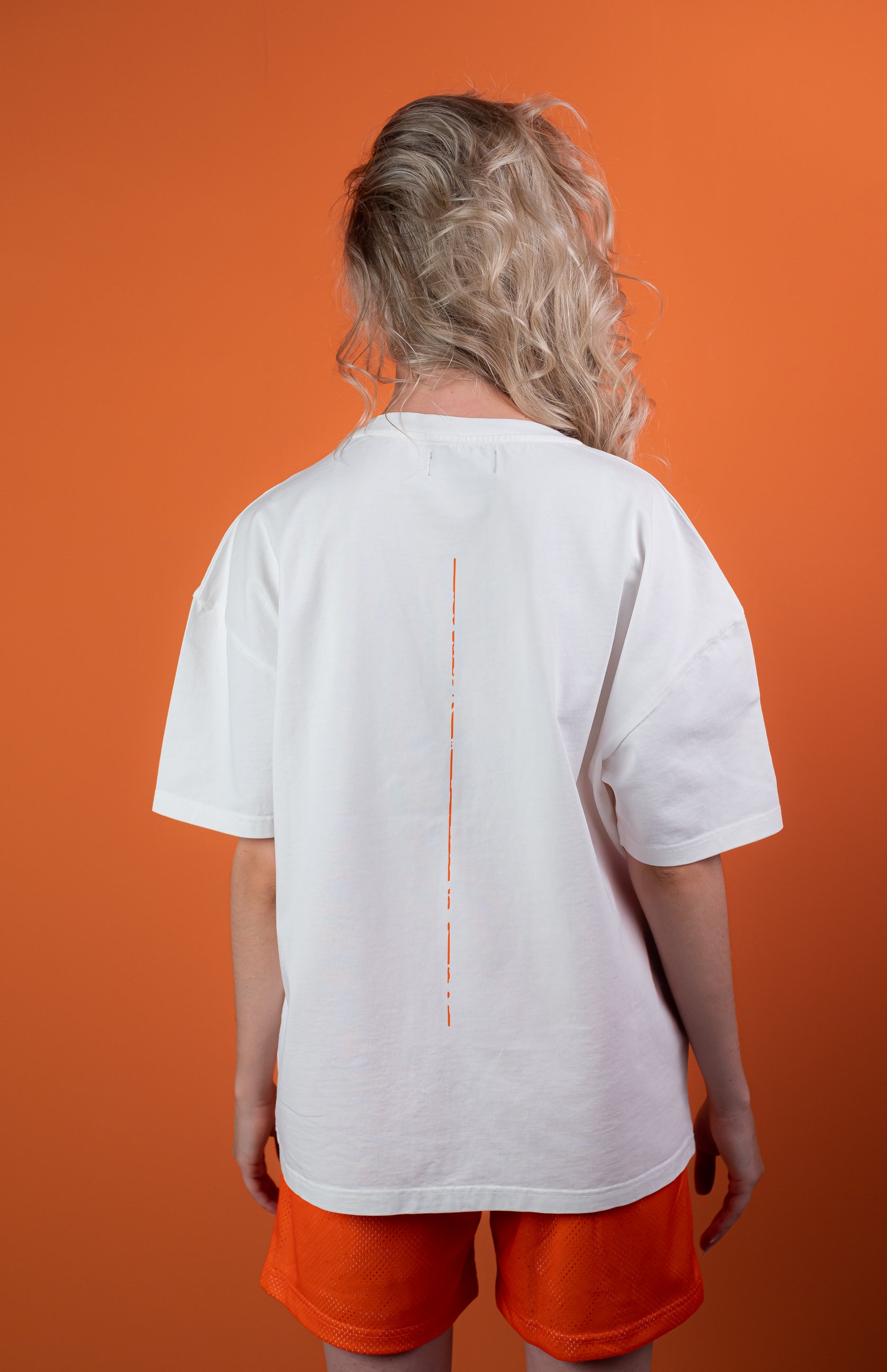 Female Model wearing White oversize tshirt with orange trace on the back