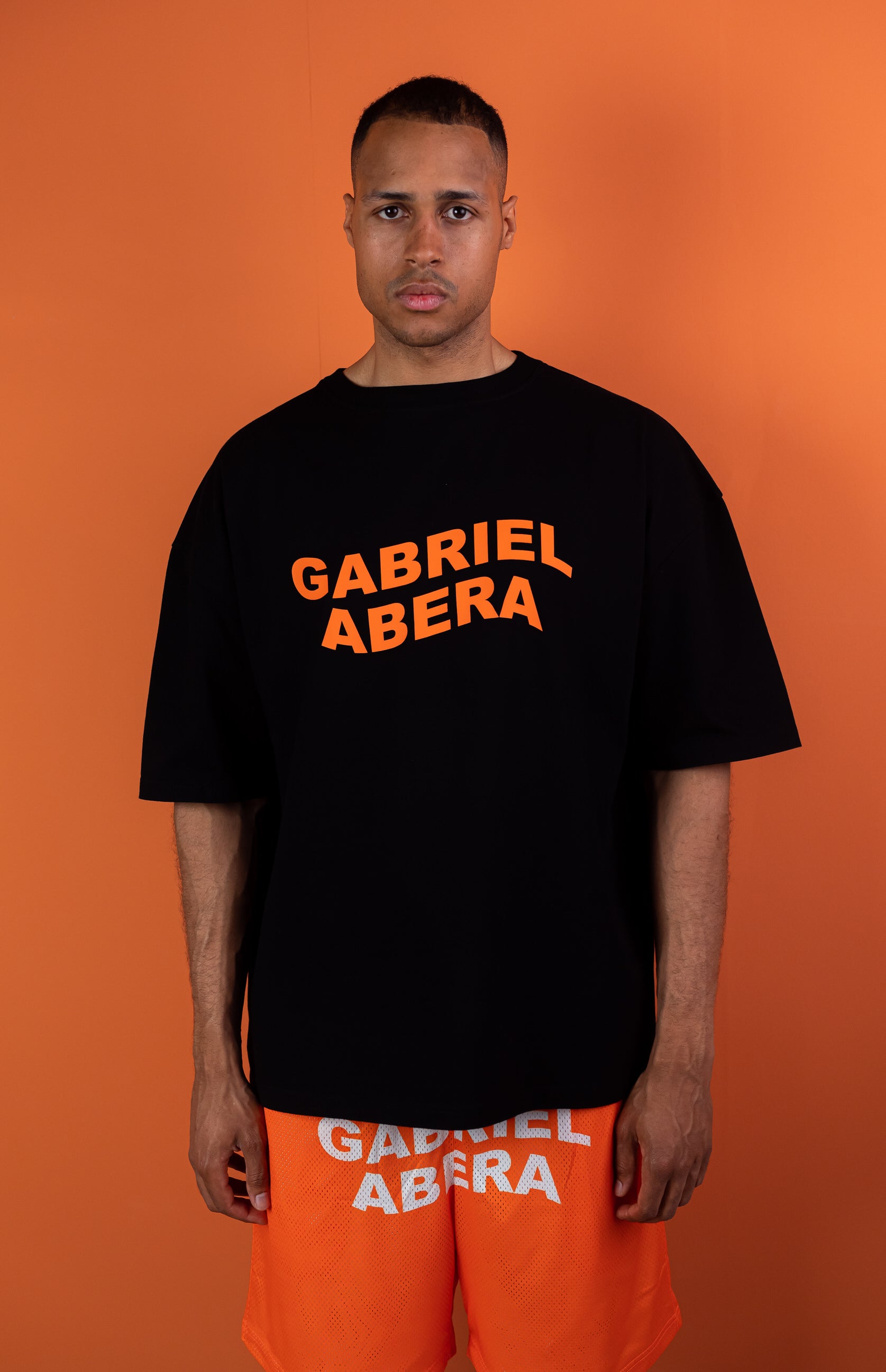 model wearing black oversie tshirt with orange wavy brand name design