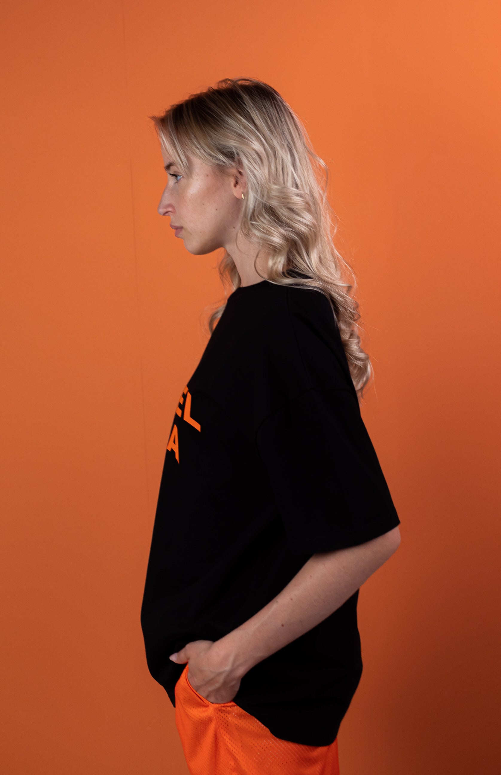 model wearing black oversie tshirt with orange wavy brand name design