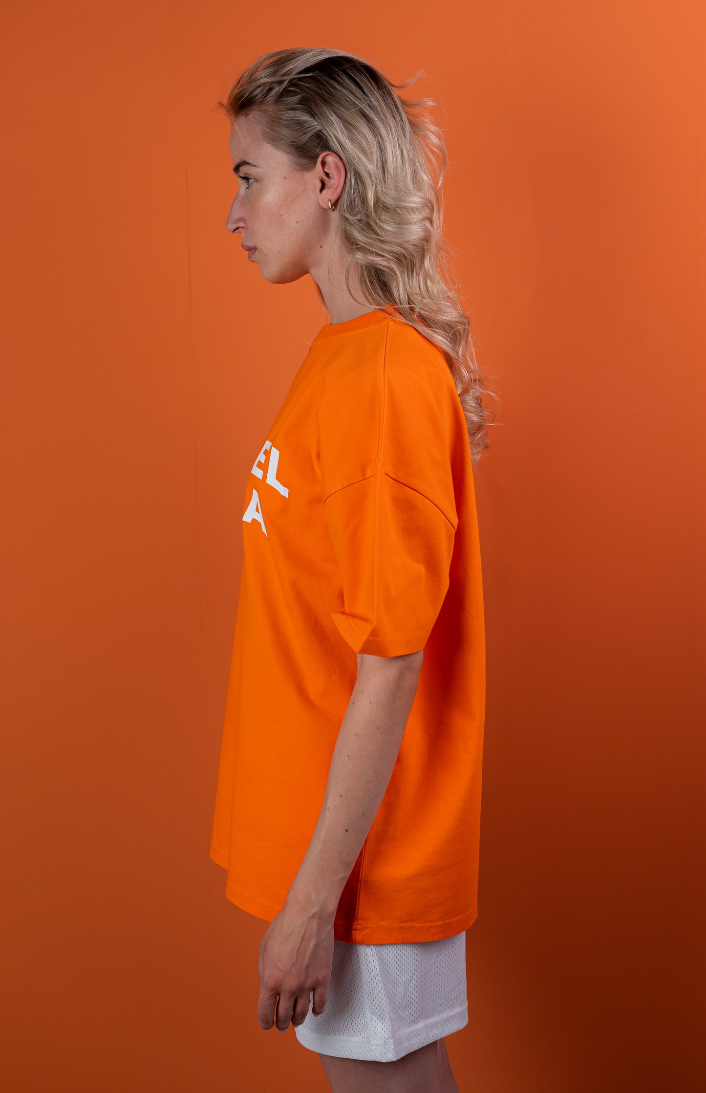 Model wearing a orange oversize tshirt with whitewavy brand name design