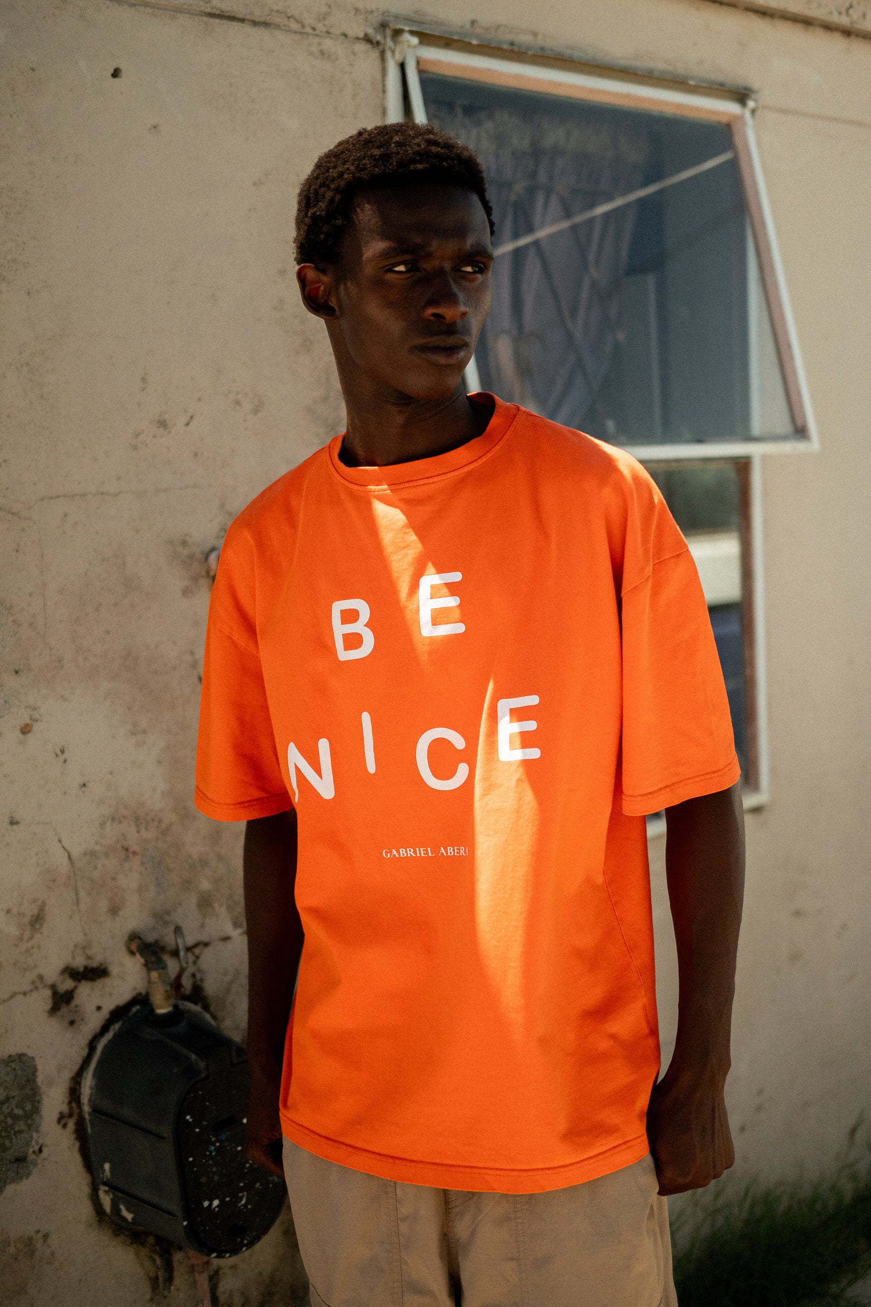 Township Model trägt orange BE NICE oversize Tee von Gabriel Abera.