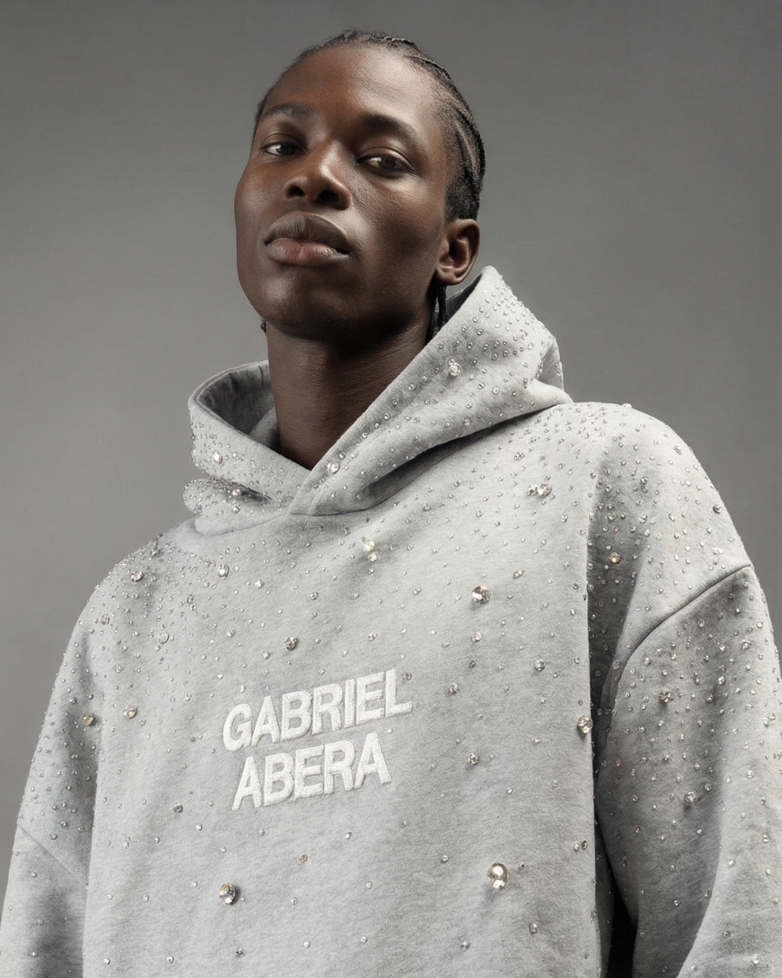 Männliches Model trägt grauen GABRIEL ABERA Universe Hoodie mit handgesetzten Rhinestones – Frontansicht im Oversized Streetwear Fit.