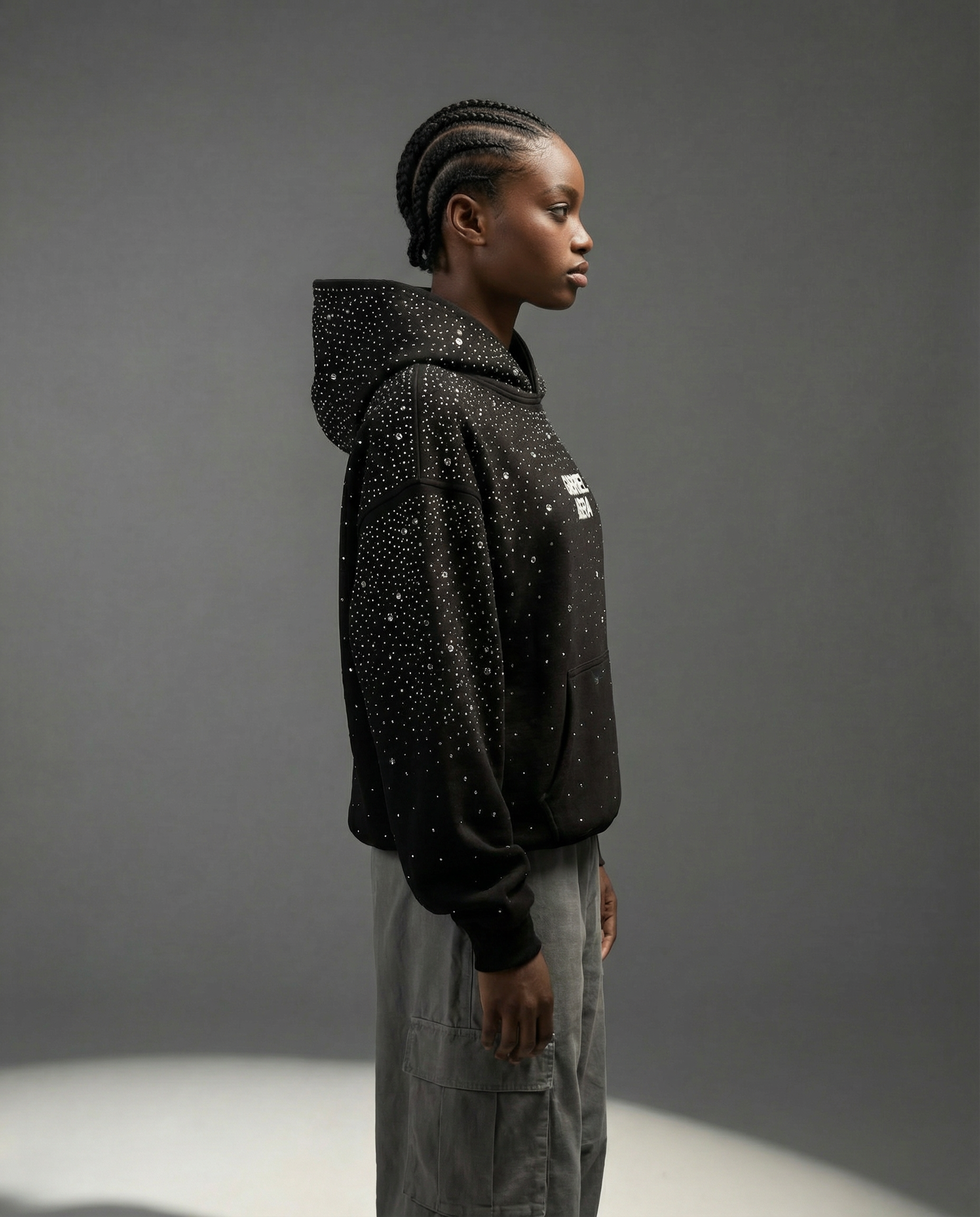 Female model wearing black oversized rhinestone hoodie by GABRIEL ABERA, subtle branding, modern studio setting