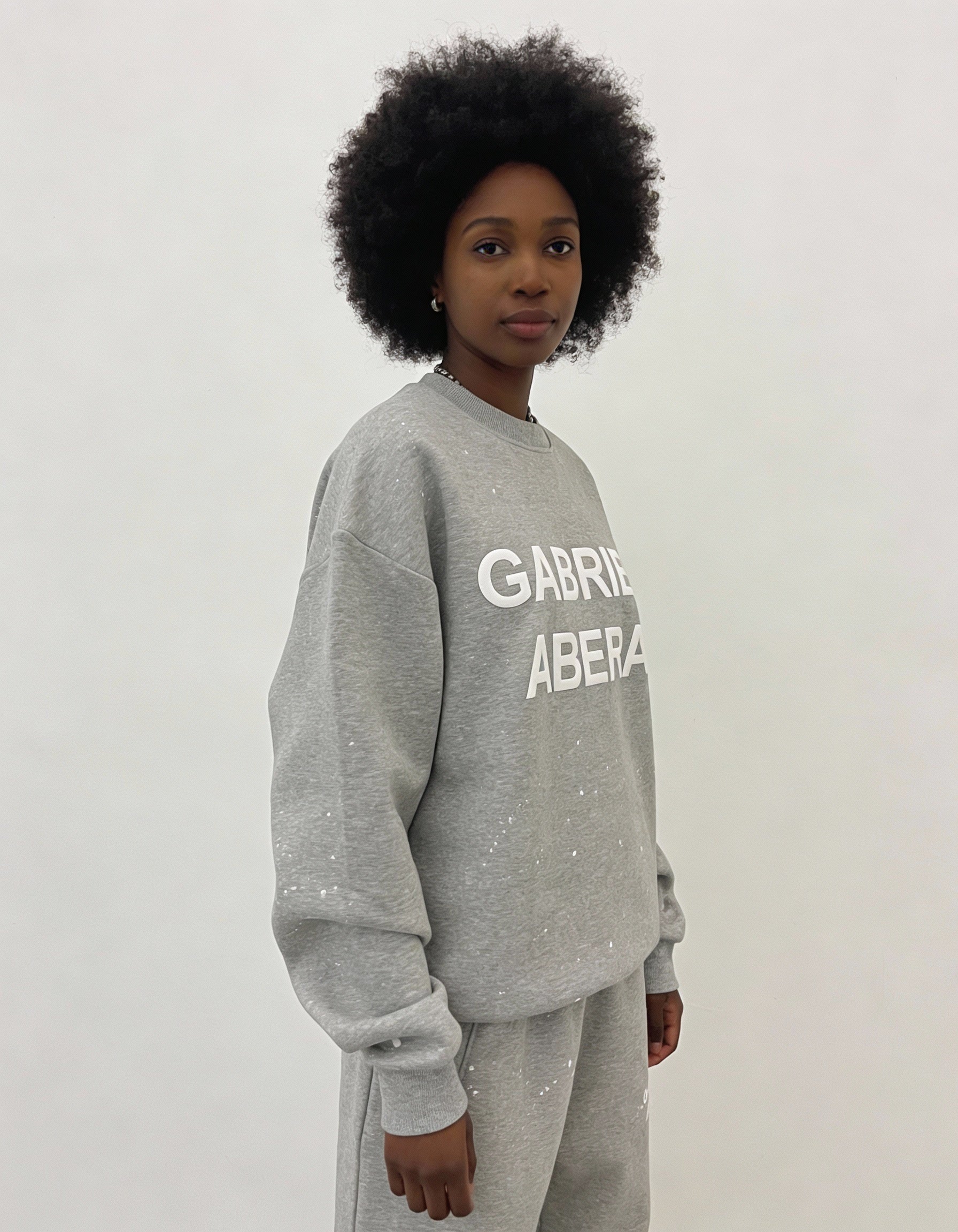 Side profile des weiblichen Models mit dem Splattered Sweater mit weißen Farbspritzern von Gabriel Abera.