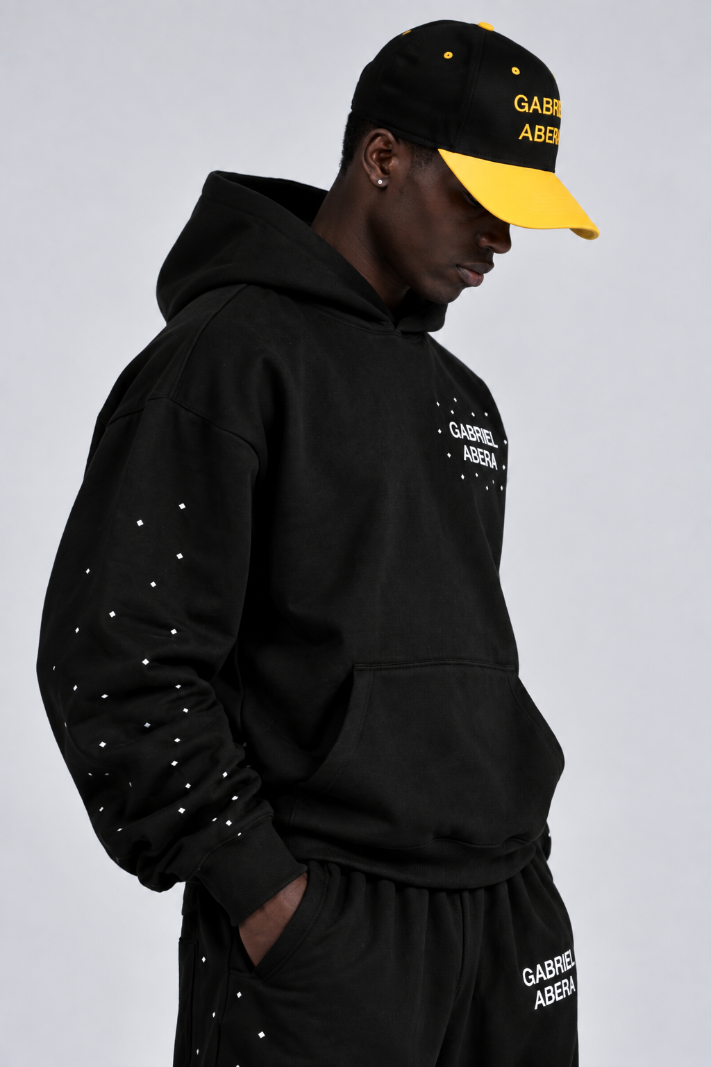 Model trägt die schwarze GABRIEL ABERA Trophy Snapback mit gelben Details im modernen Unisex Streetwear Look