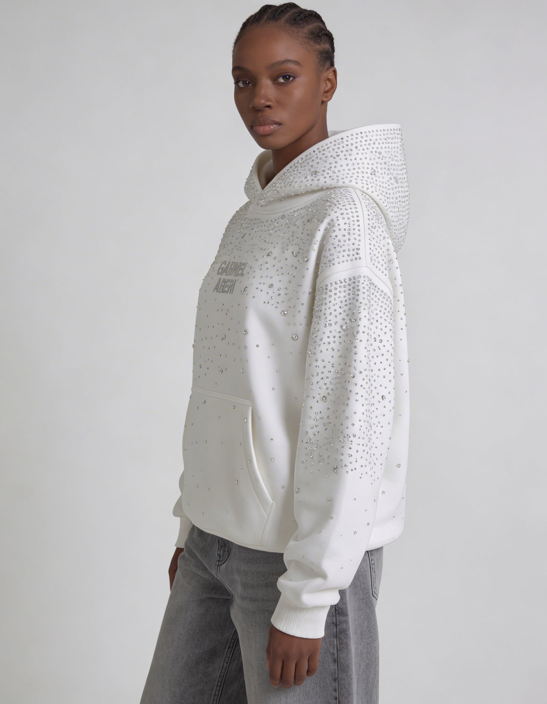 Weibliches Model im GABRIEL ABERA Rhinestone Hoodie Off White – eleganter Unisex Streetwear Look mit funkelnden Strass-Details.