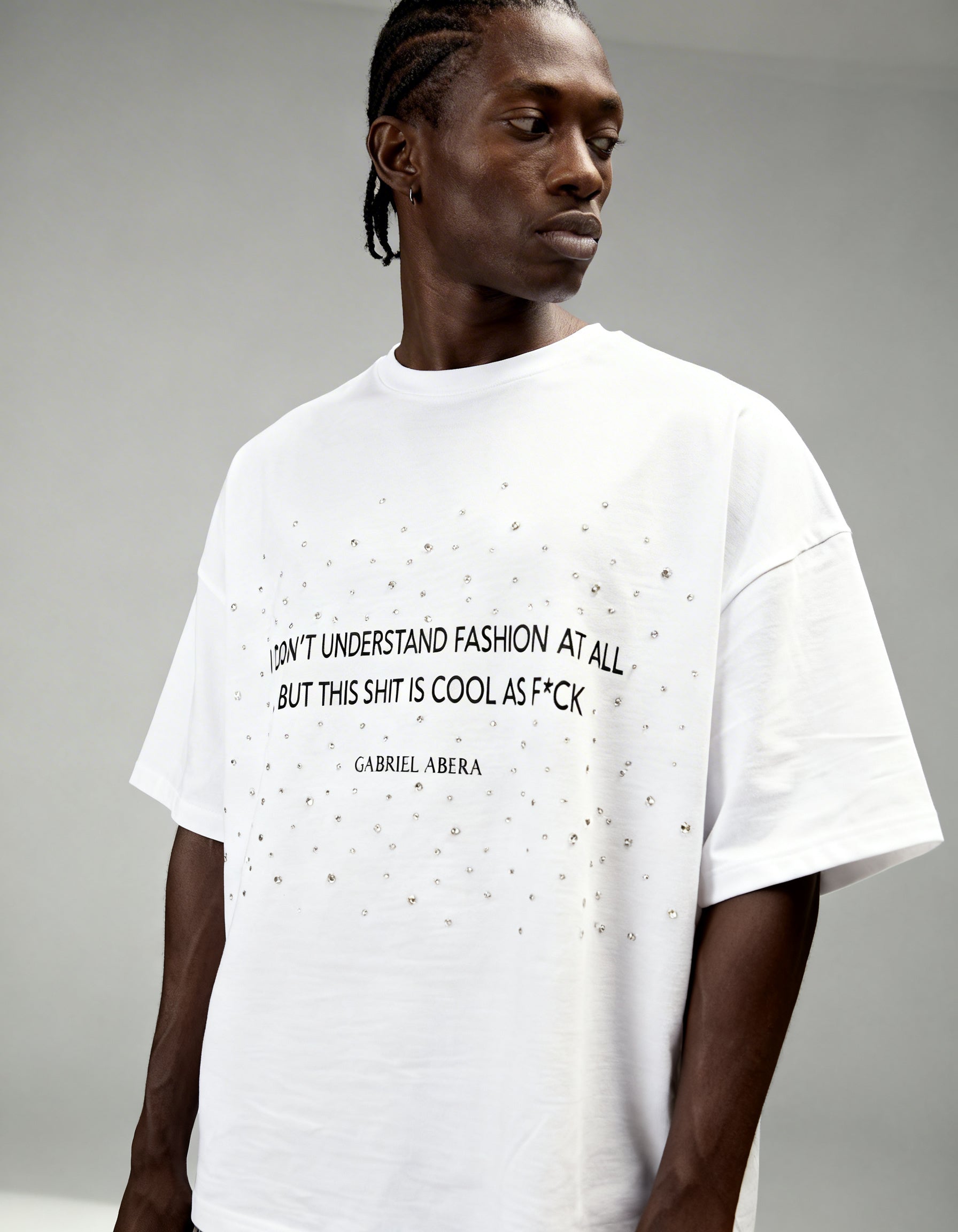 White oversized boxy rhinestone T-shirt by GABRIEL ABERA featuring statement text print and scattered rhinestone embellishments on the chest.