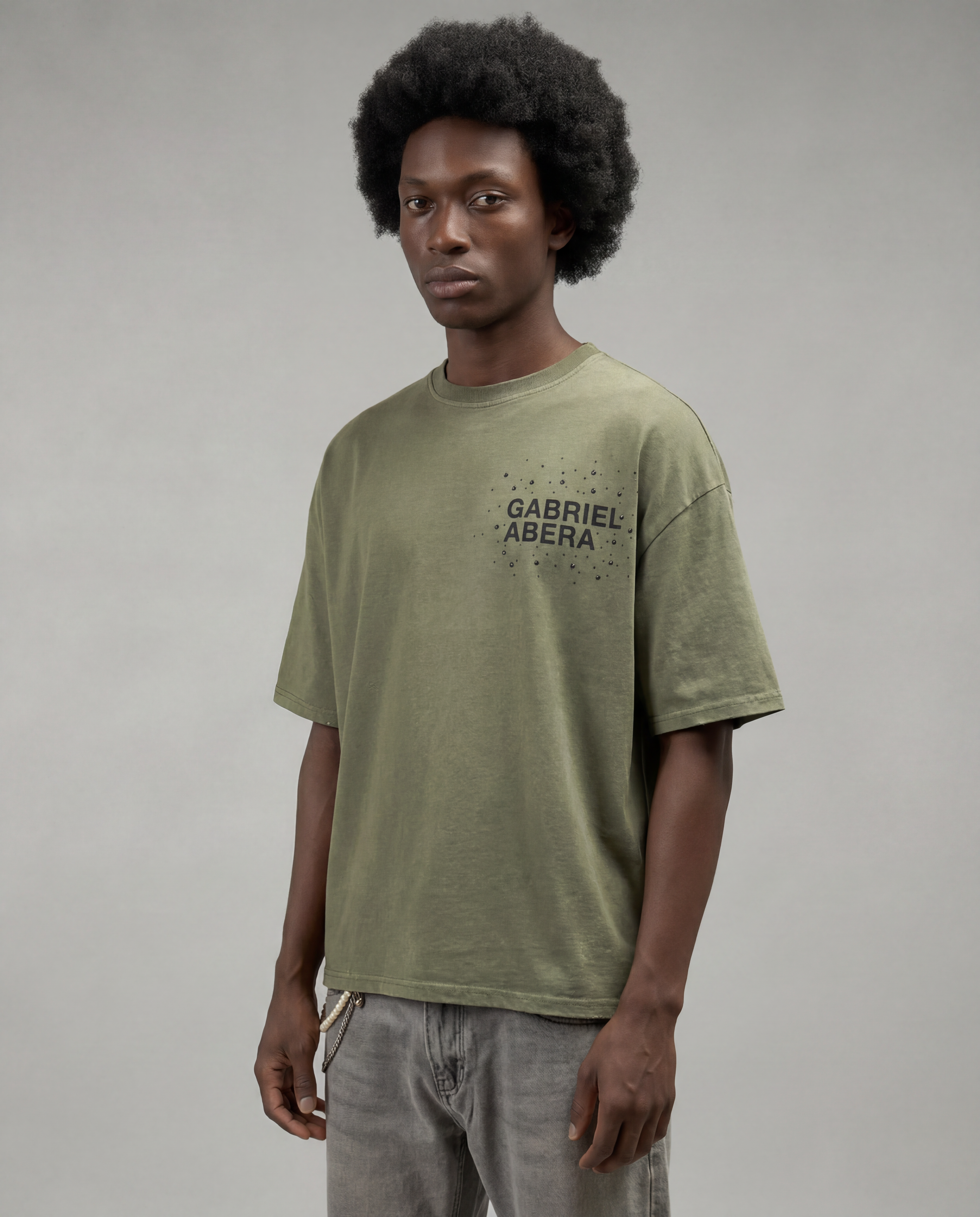 Male model wearing the Gabriel Abera Rhinestone Logo Tee in olive – full-length front view, oversized silhouette, rhinestone chest logo, grey background