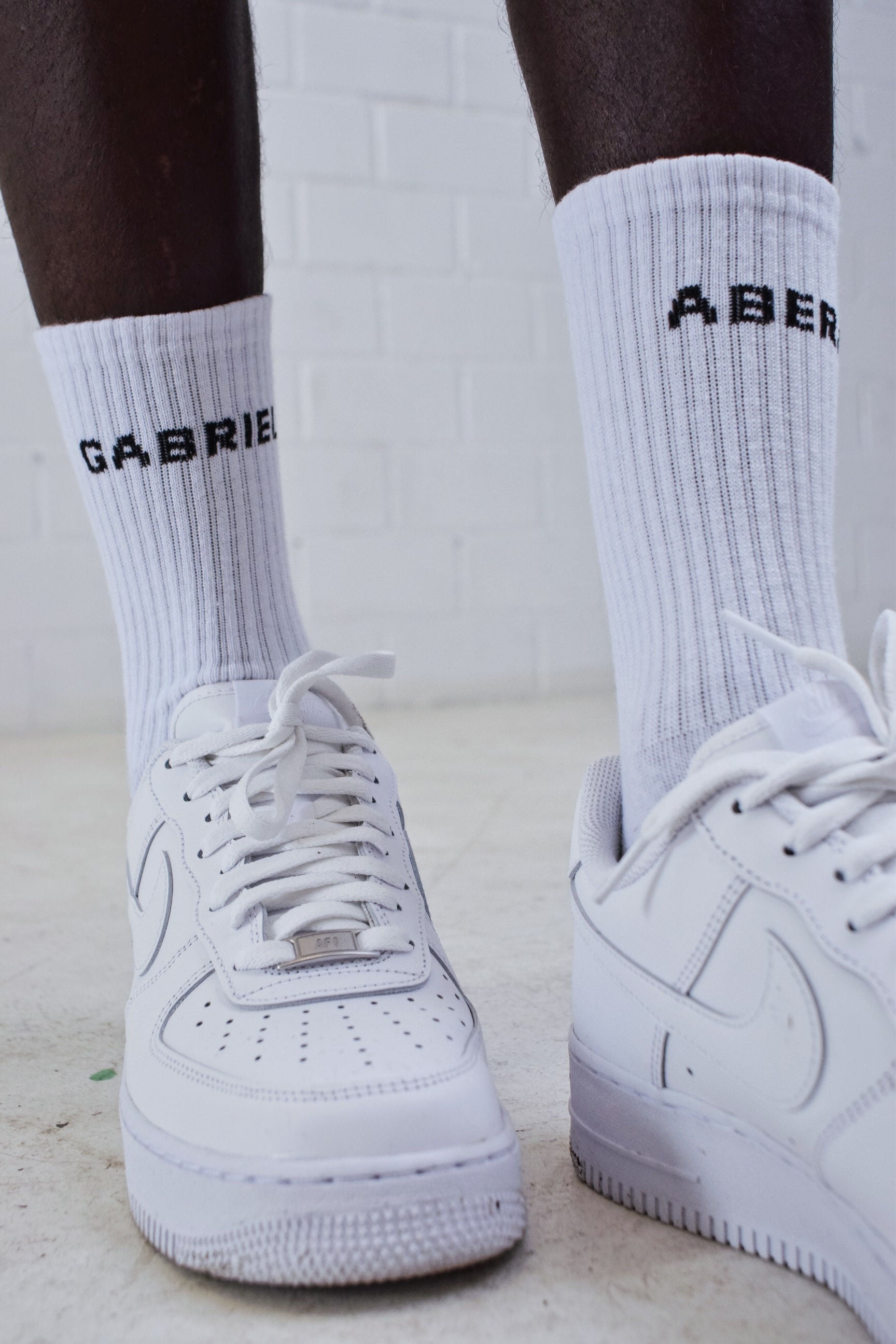 Model wearing White pair of socks with black brand name print