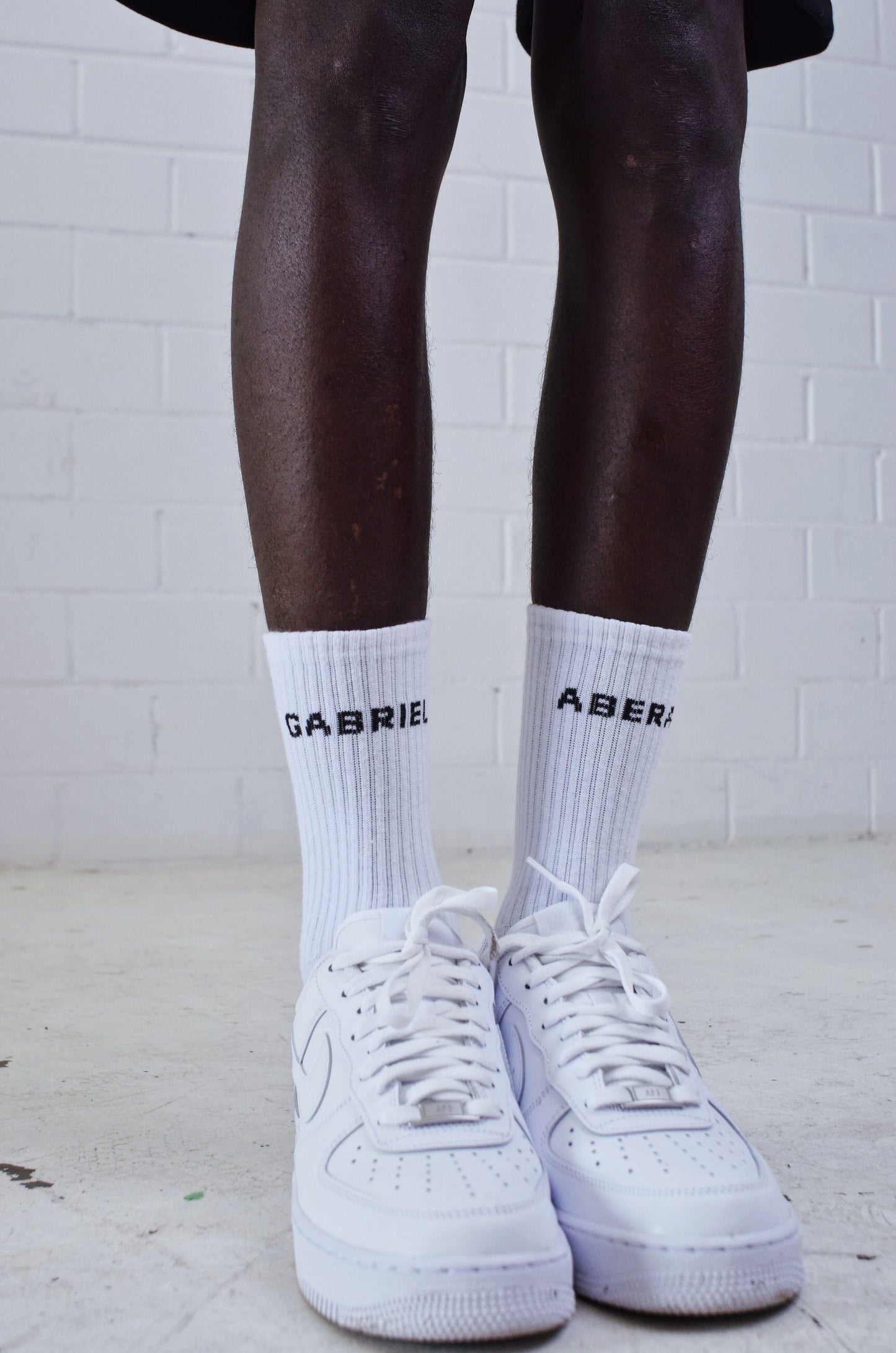 Model wearing White pair of socks with black brand name print