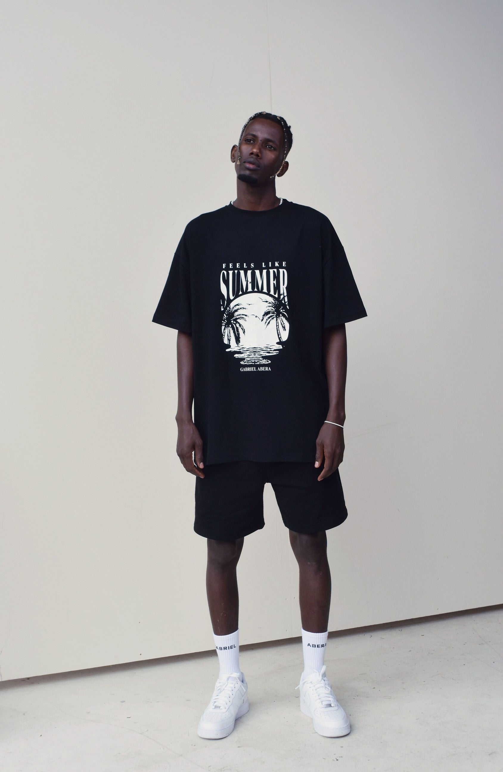 Male model wearing a Black oversize tshirt with round white summer design on the front 