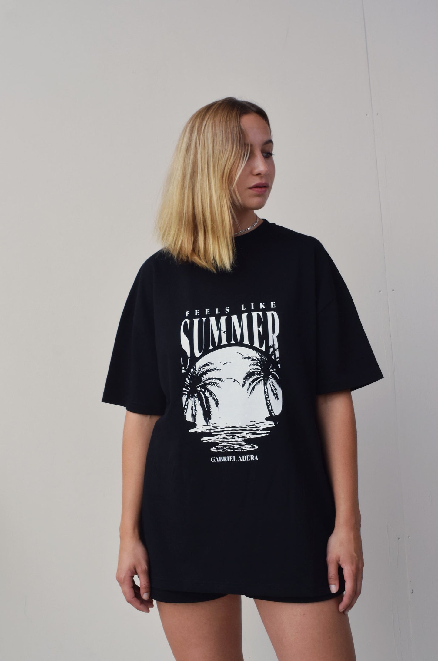 Female model wearing a Black oversize tshirt with round white summer design on the front 