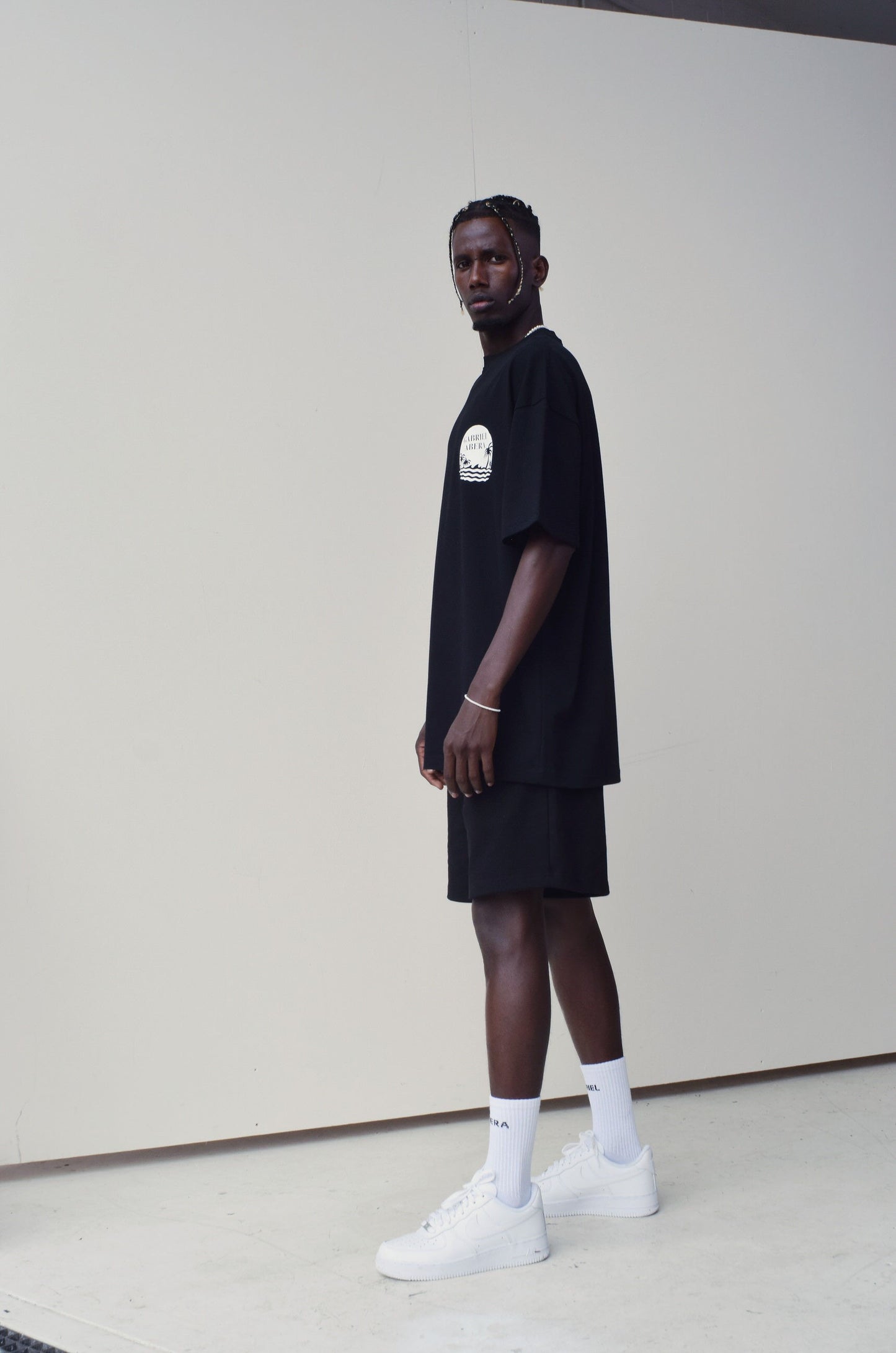 Male Model wearing a Black oversize Tshirt with round brand design