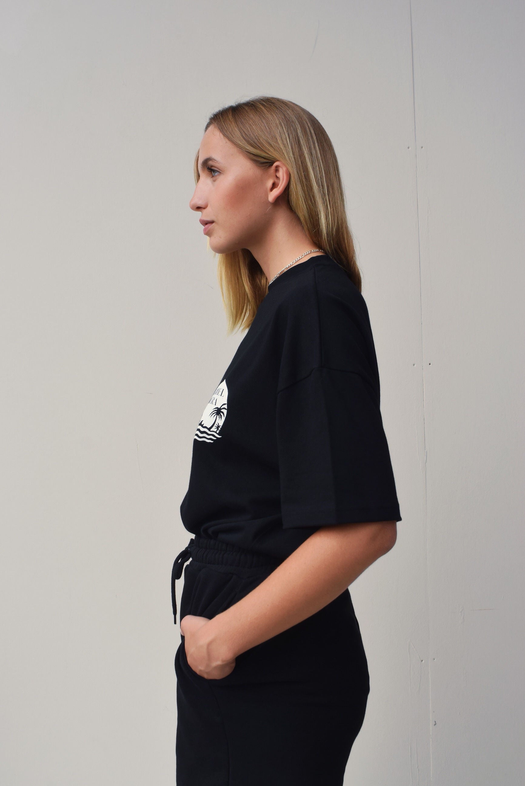 Female model wearing a Black oversize Tshirt with round brand design