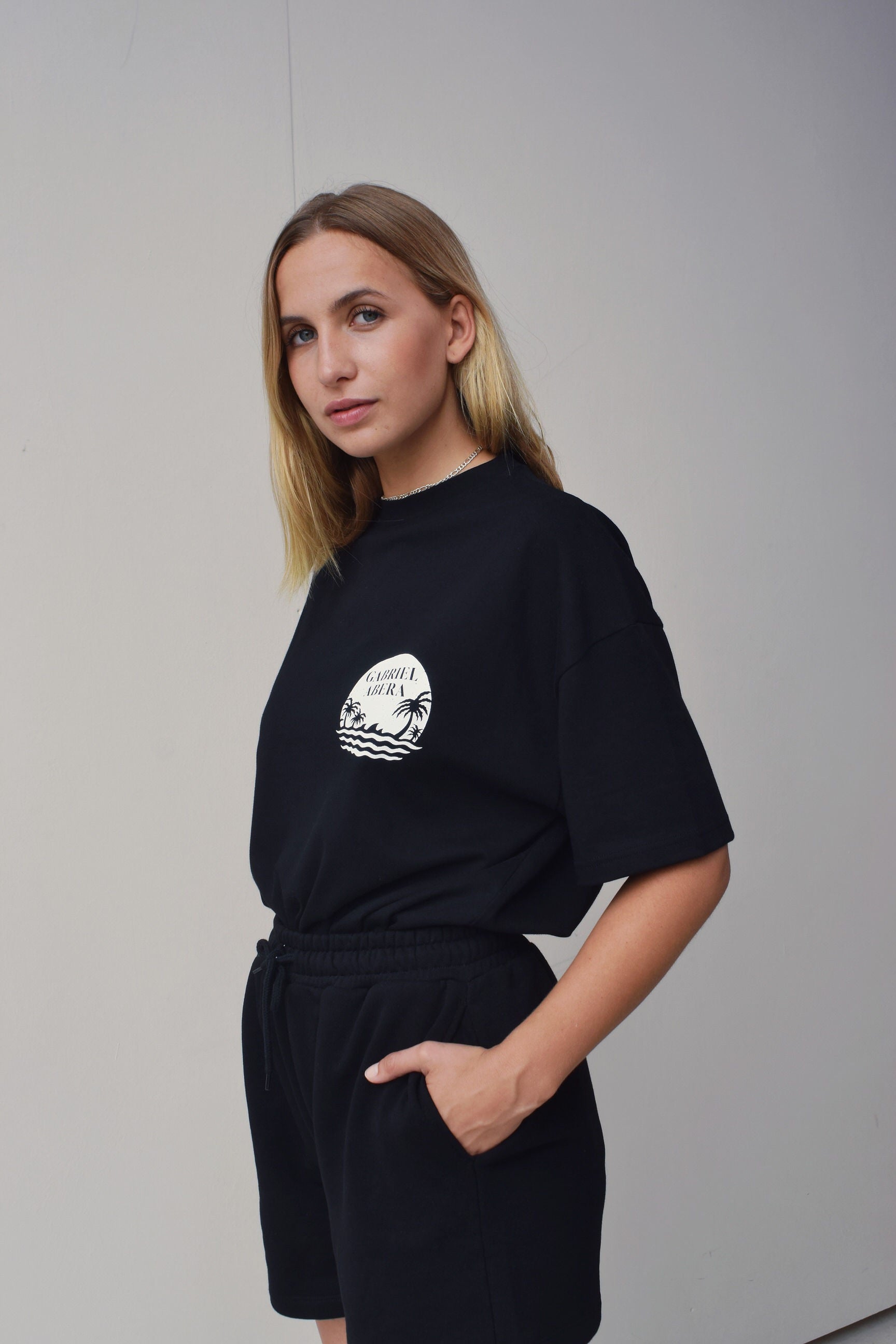Female model wearing a Black oversize Tshirt with round brand design