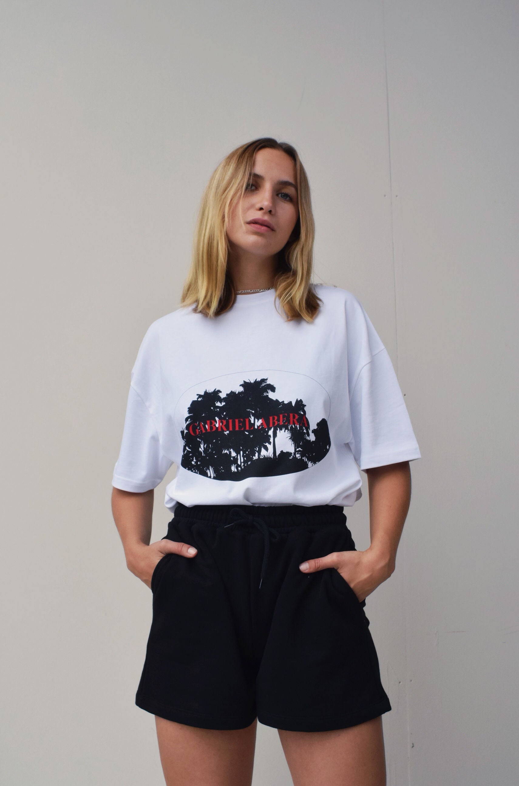 Female Model wearing a White oversize tshirt with black and red summer design in the front 