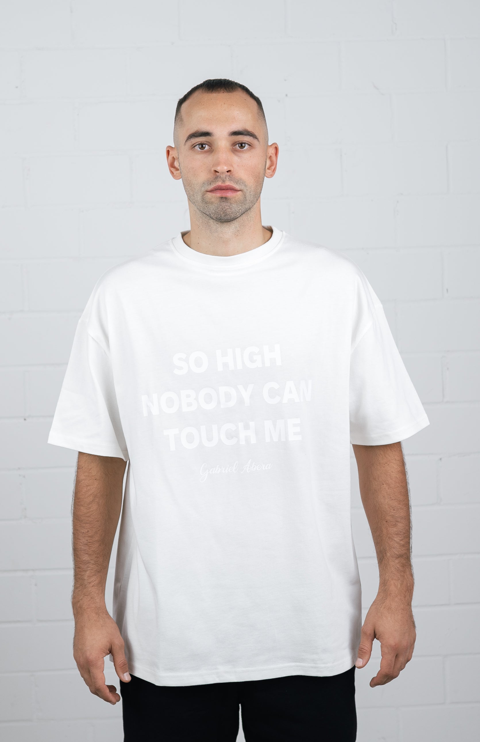 male model wearing a White oversize tshirt with white so high nobody can touch me design in the front
