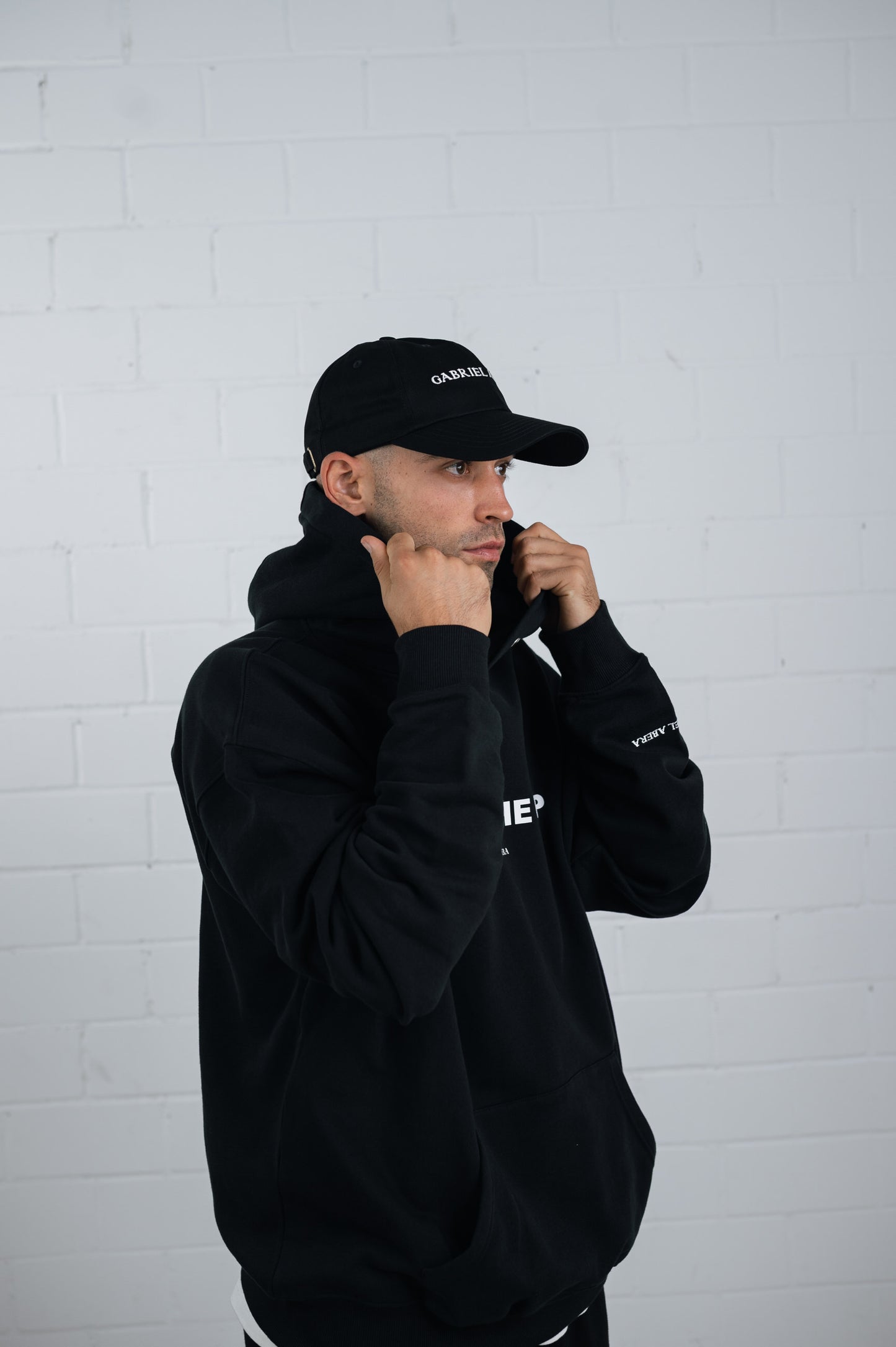 Male model wearing a Black cap with brand name embroidery