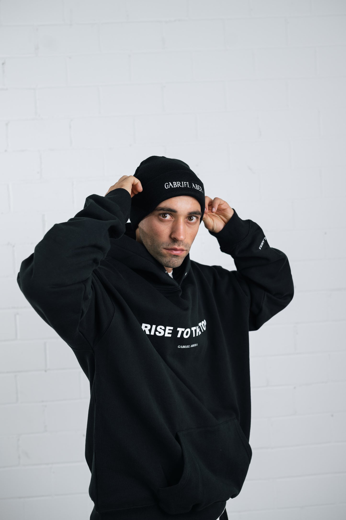 Male model wearing a Black beanie with brand name embroidery