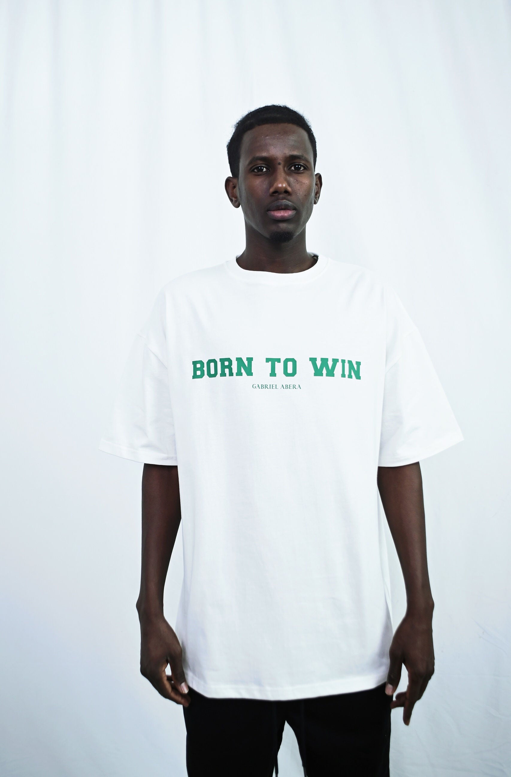 Male model wearing a white oversize tshirt with born to win design on the front