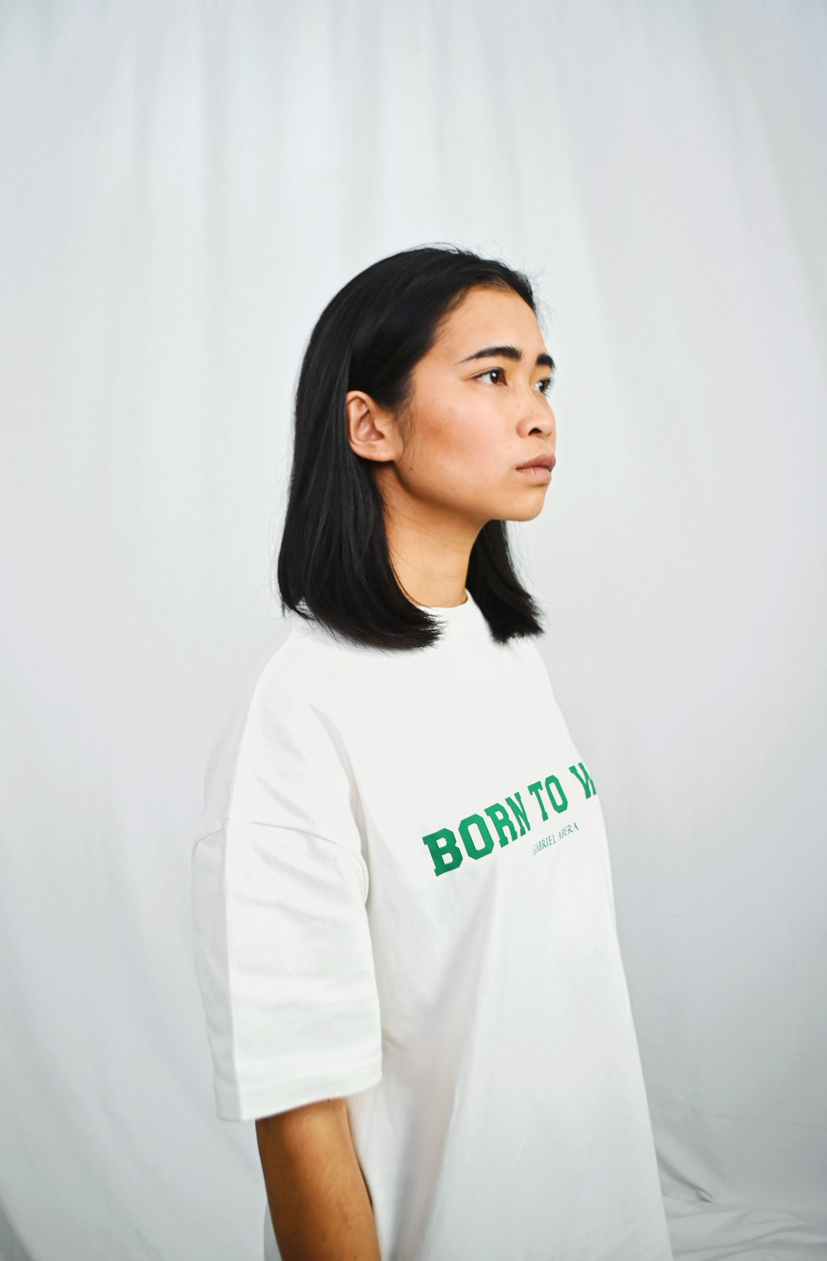 Female model wearing a White oversize tshirt with born to win design on the front