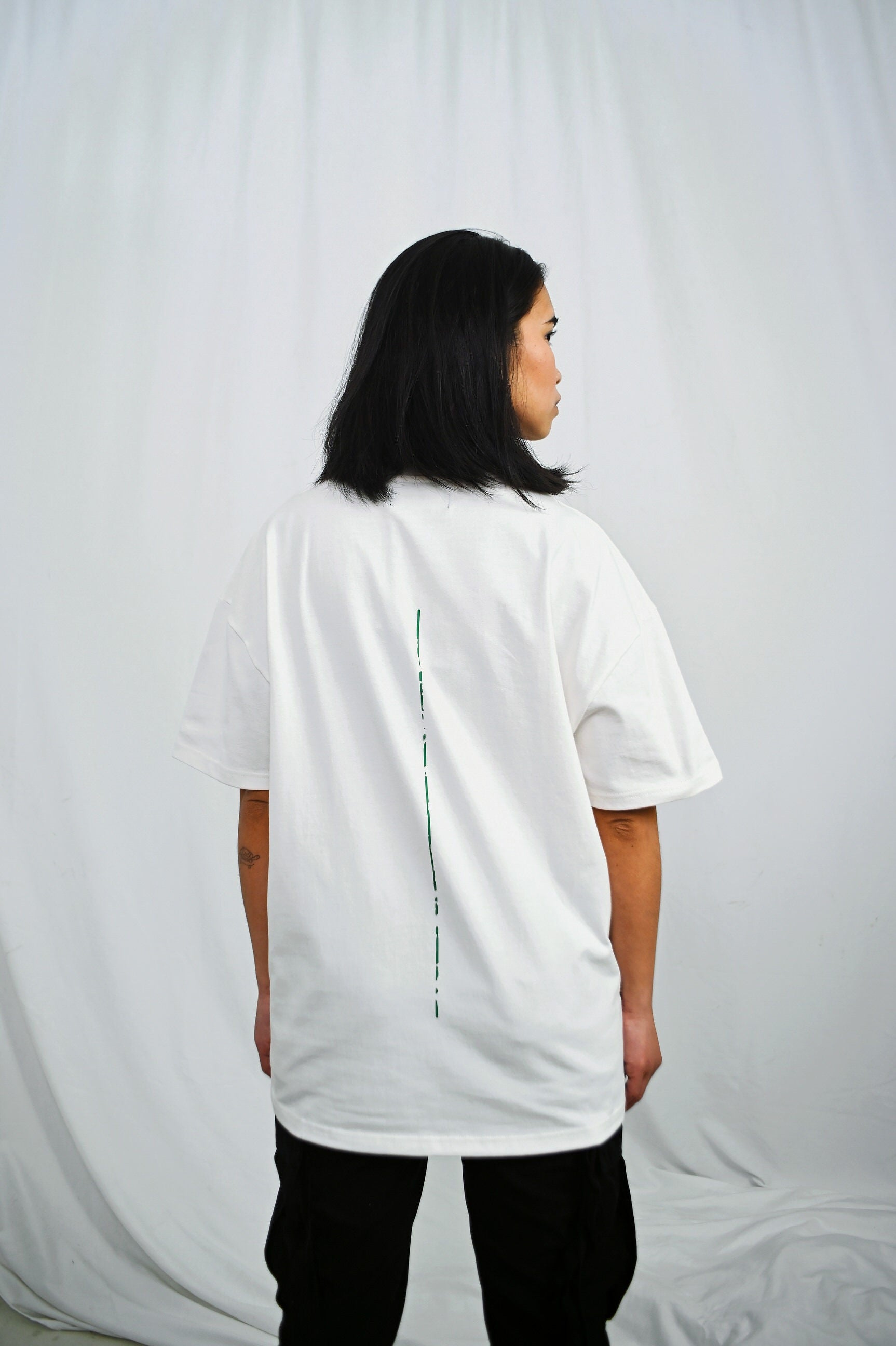 Female model wearing a White oversize tshirt with green trace on the back