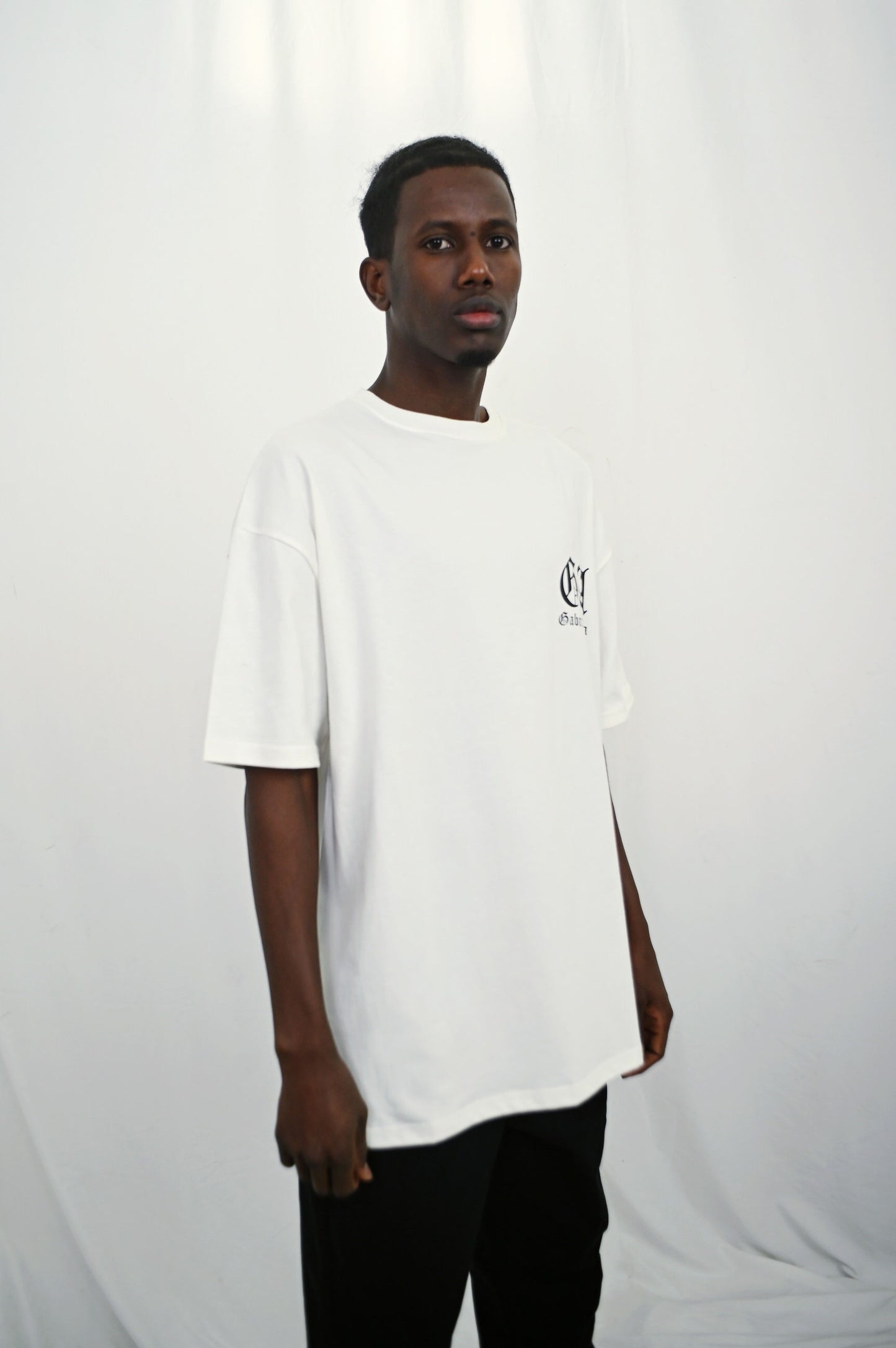 Male model wearing a white oversize Tshirt with brand design on the front