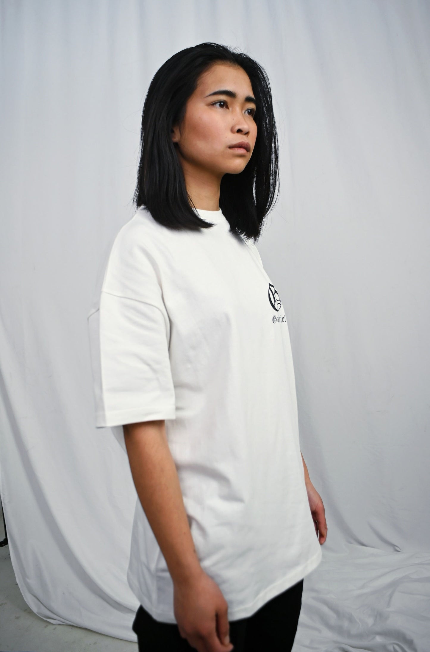 Female model wearing a white oversize Tshirt with brand design on the front