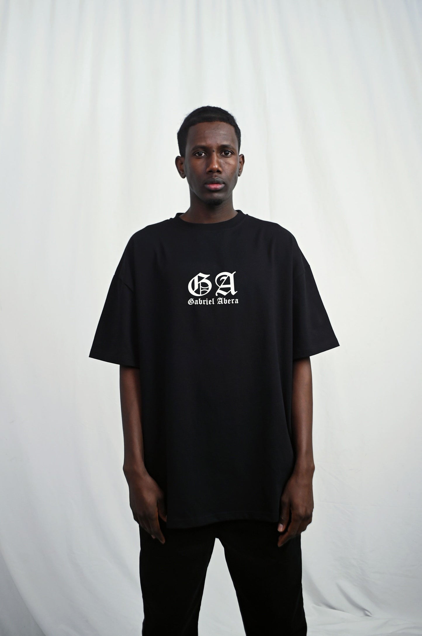 Male model wearing s Black oversize Tshirt with brand design on the front