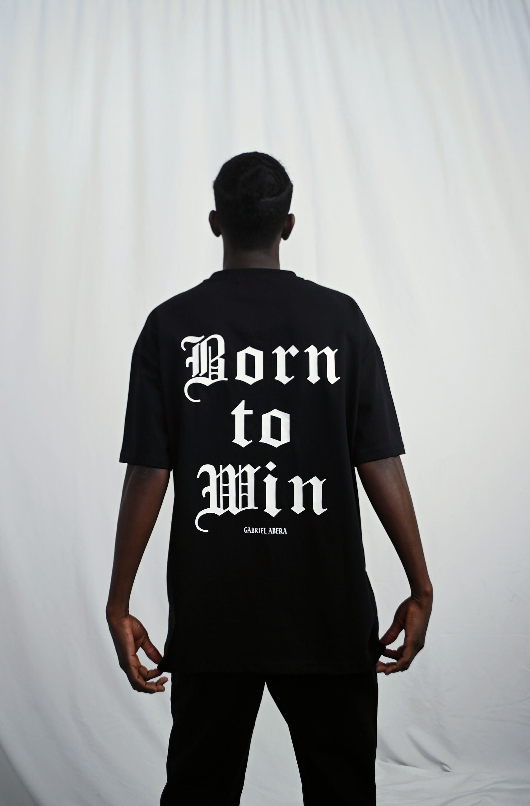 Male model wearing s Black oversize Tshirt with born to win design on the back