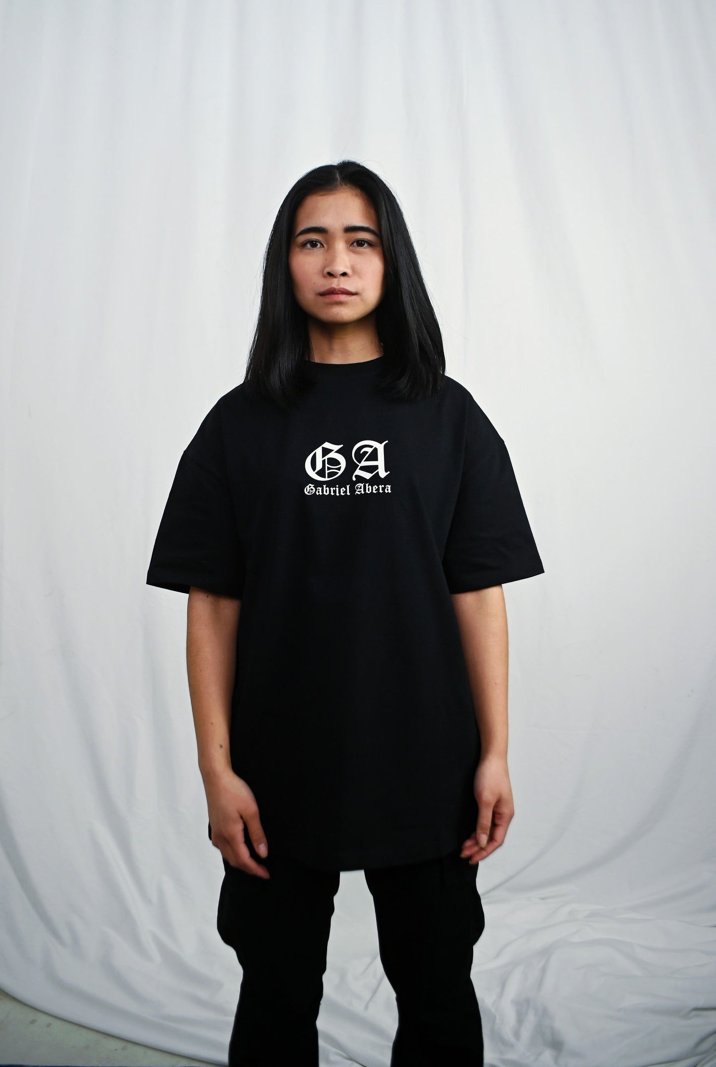 Female model wearing s Black oversize Tshirt with brand design on the front