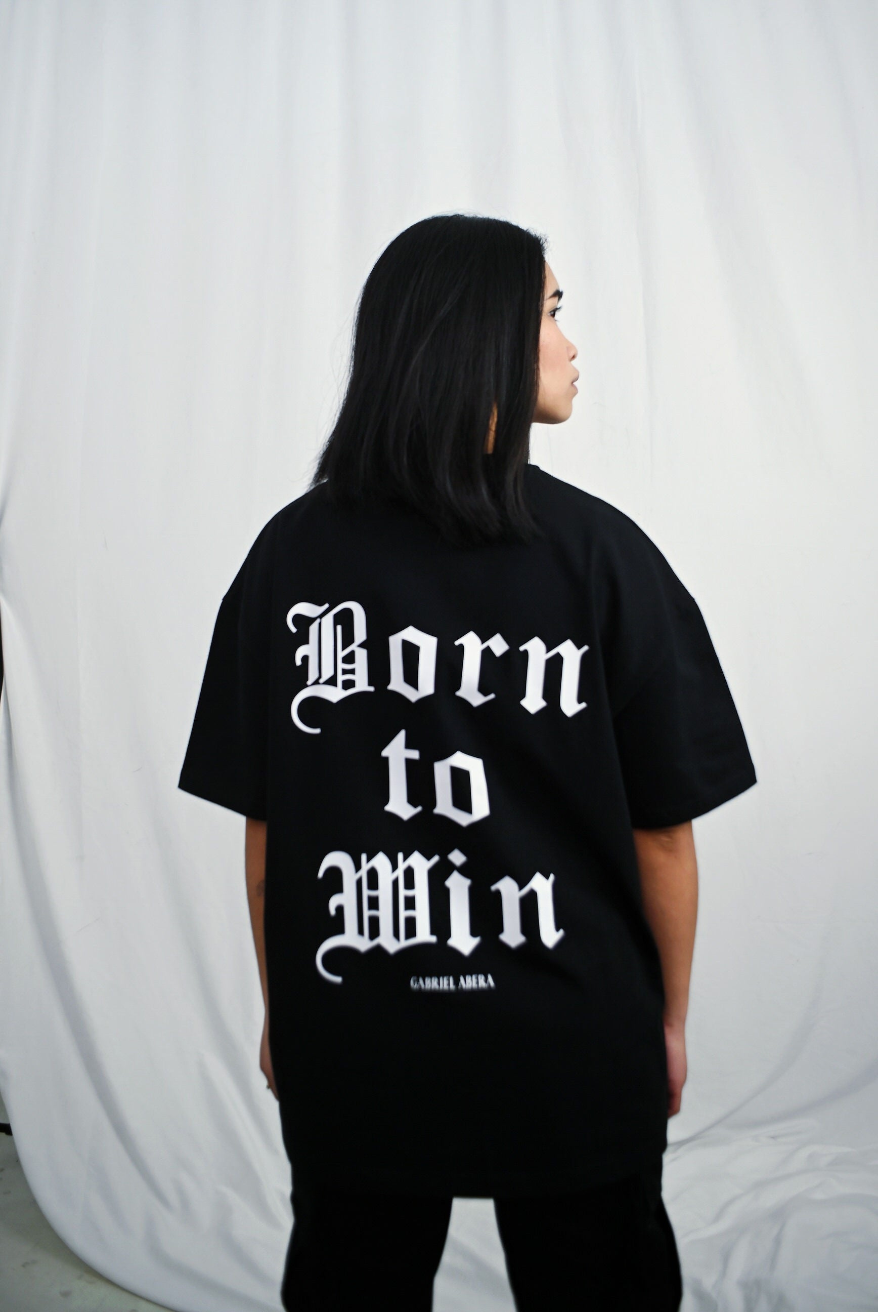 Female model wearing s Black oversize Tshirt with born to win design on the back