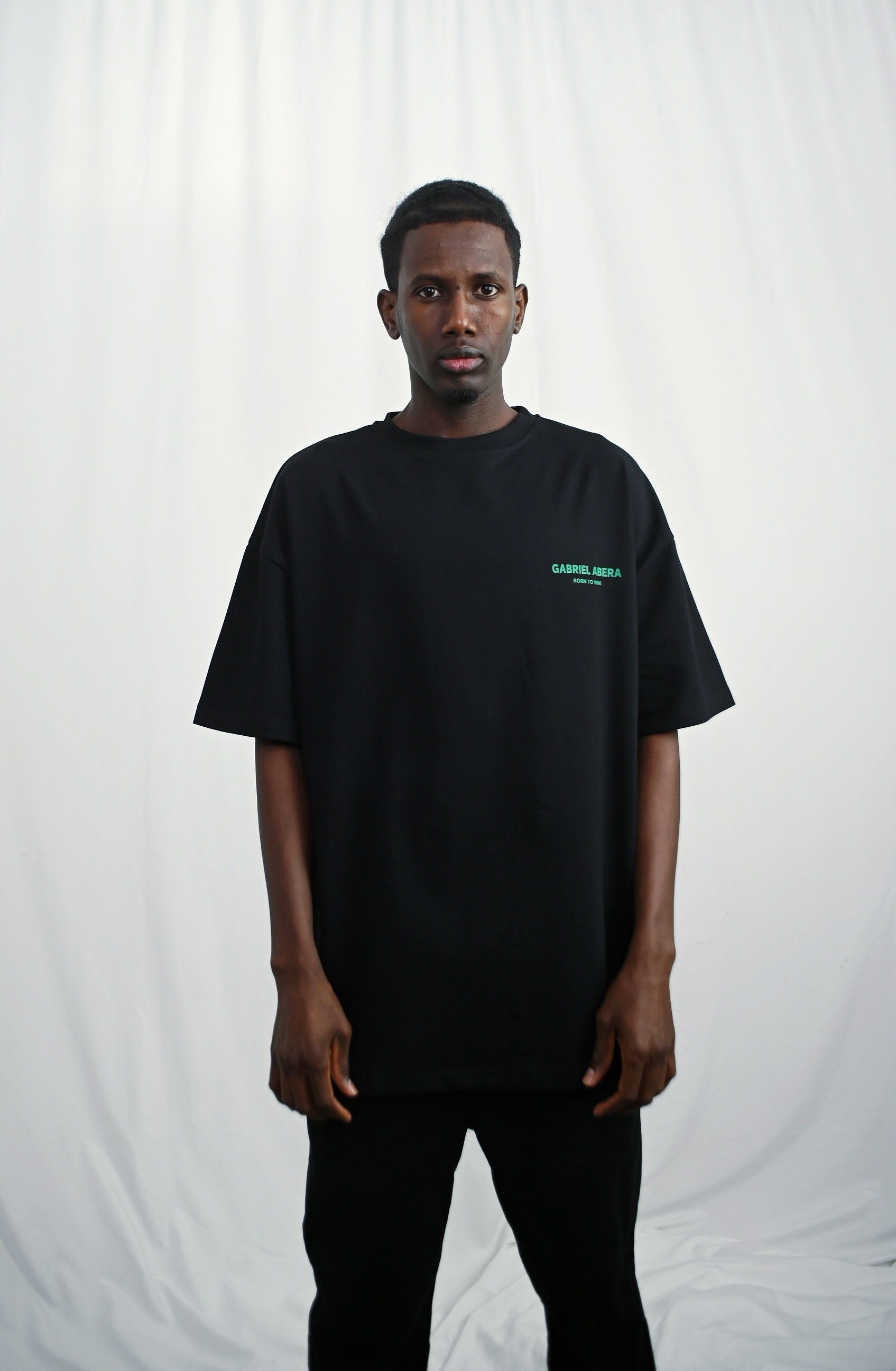 Male model wearing a Black oversize tshirt with green born to win design on the back
