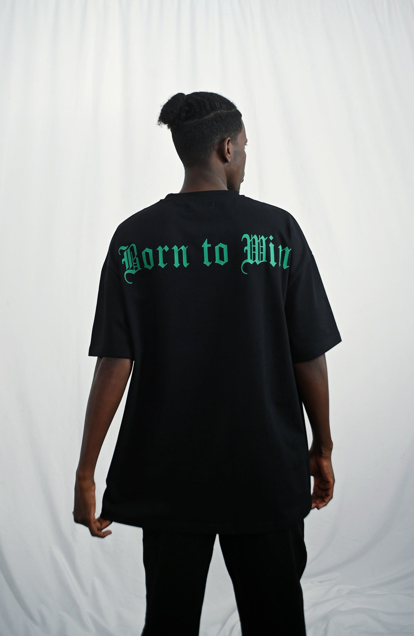 Male model wearing a Black oversize tshirt with green born to win design on the back